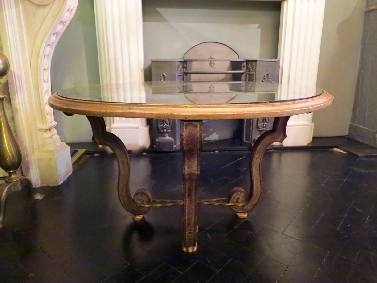 An early to mid-20th century neoclassical circular cocktail table with distressed mirrored top, giltwood frame, brass rope twist stretcher and gilt paw feet. By French Designer Marcel Dolt.