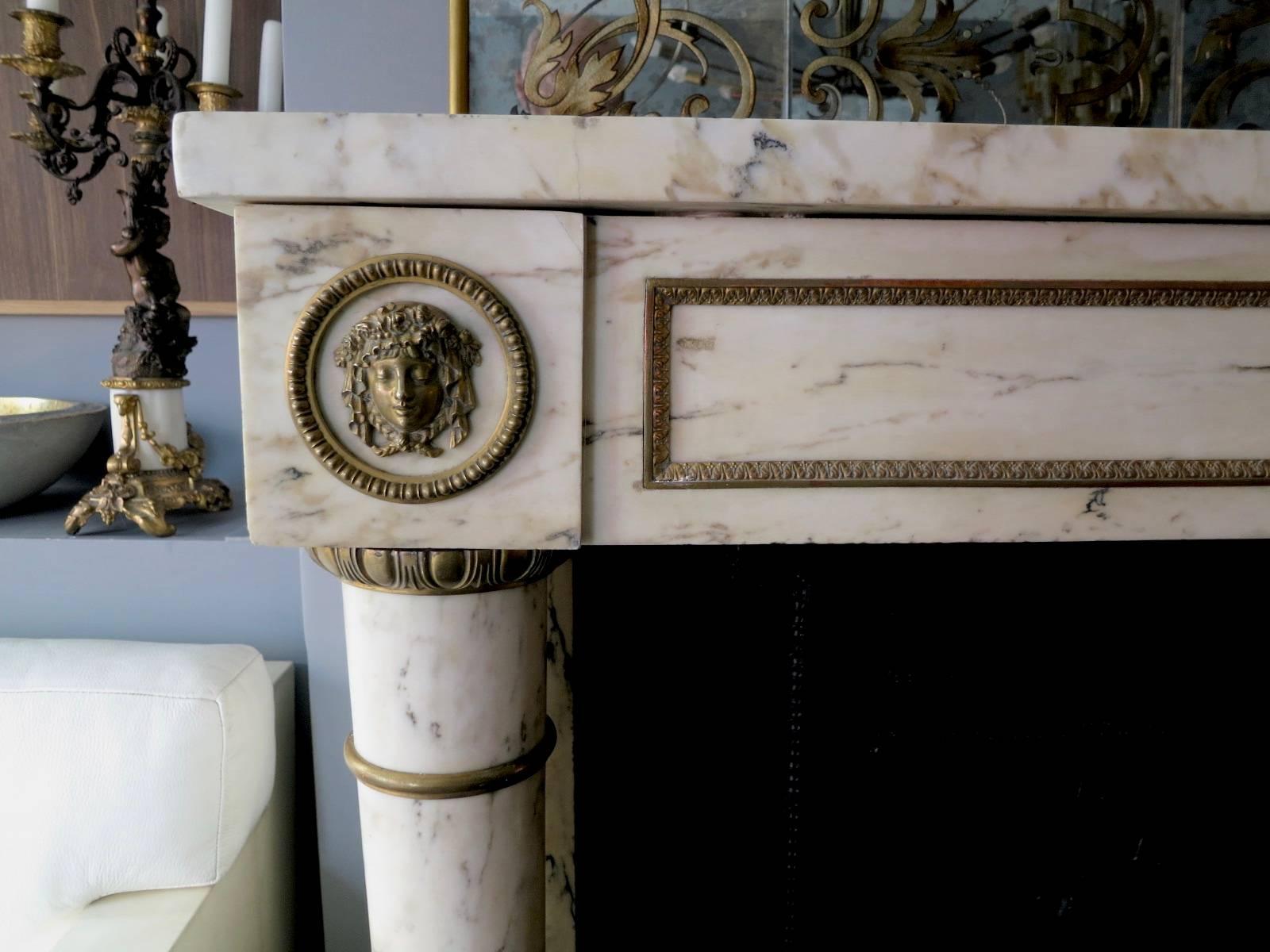 An antique French fireplace in quality breche marble with ormolu mounts and original cast iron chamber. In typical Empire Style, and well-proportioned having fine tapering columns supported on square foot blocks and ormolu mounts, again caped with
