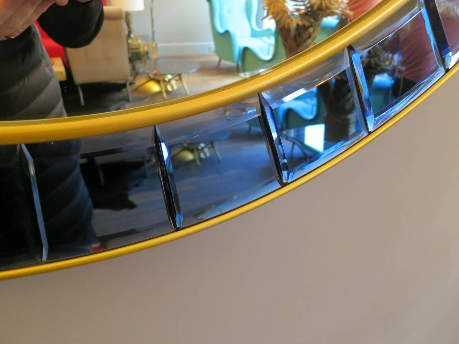 A large circular mirror, with brass framed blue segmented cut-glass border.

Cristal Arte Torino, Italy.