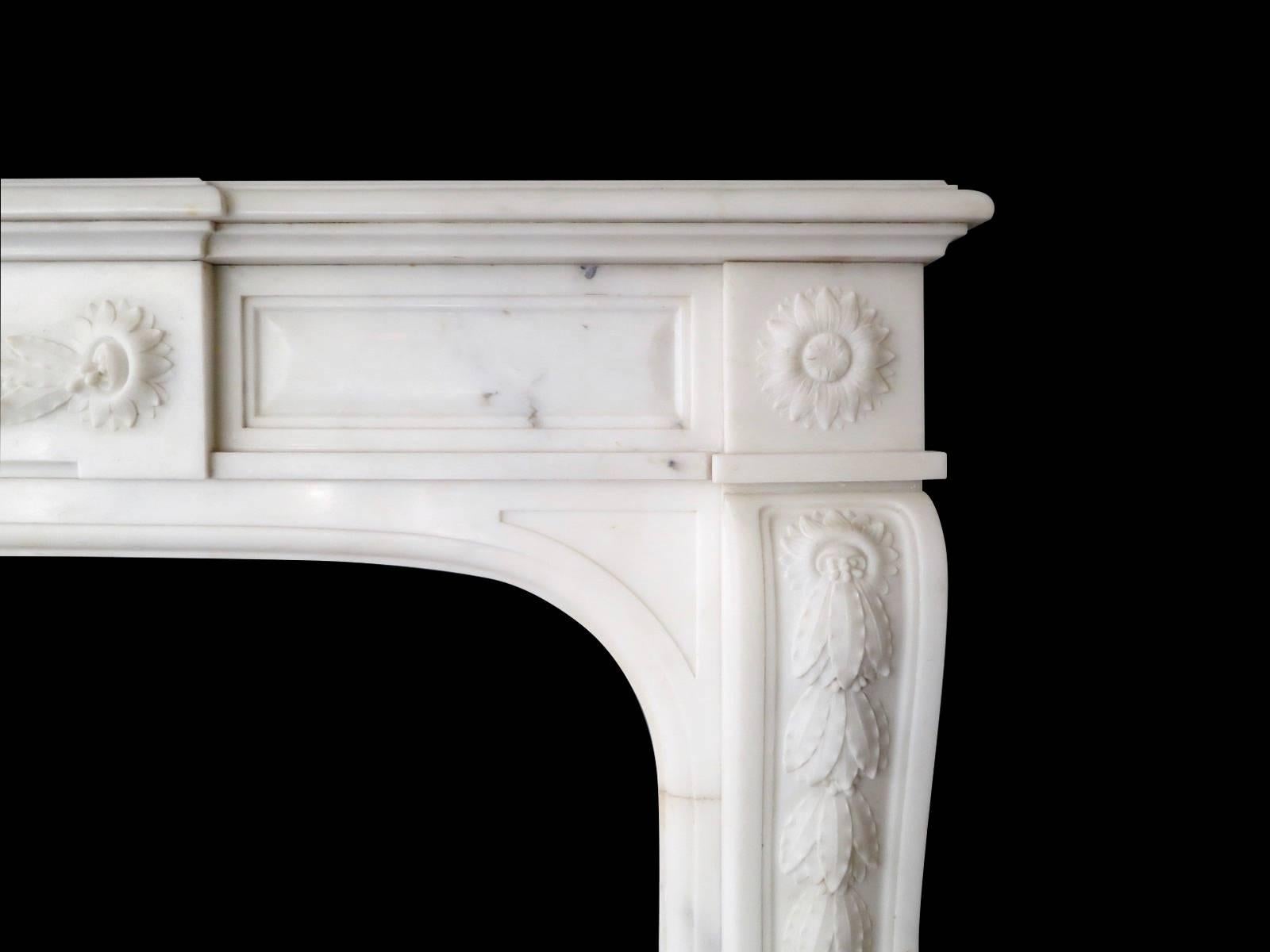 A very good quality 19th century Louis XVI style fireplace in Italian statuary white marble. The console jambs with carved descending laurel leaf surmounted by circular floral carved corner blocks. The centre tablet with conforming carving, flanked