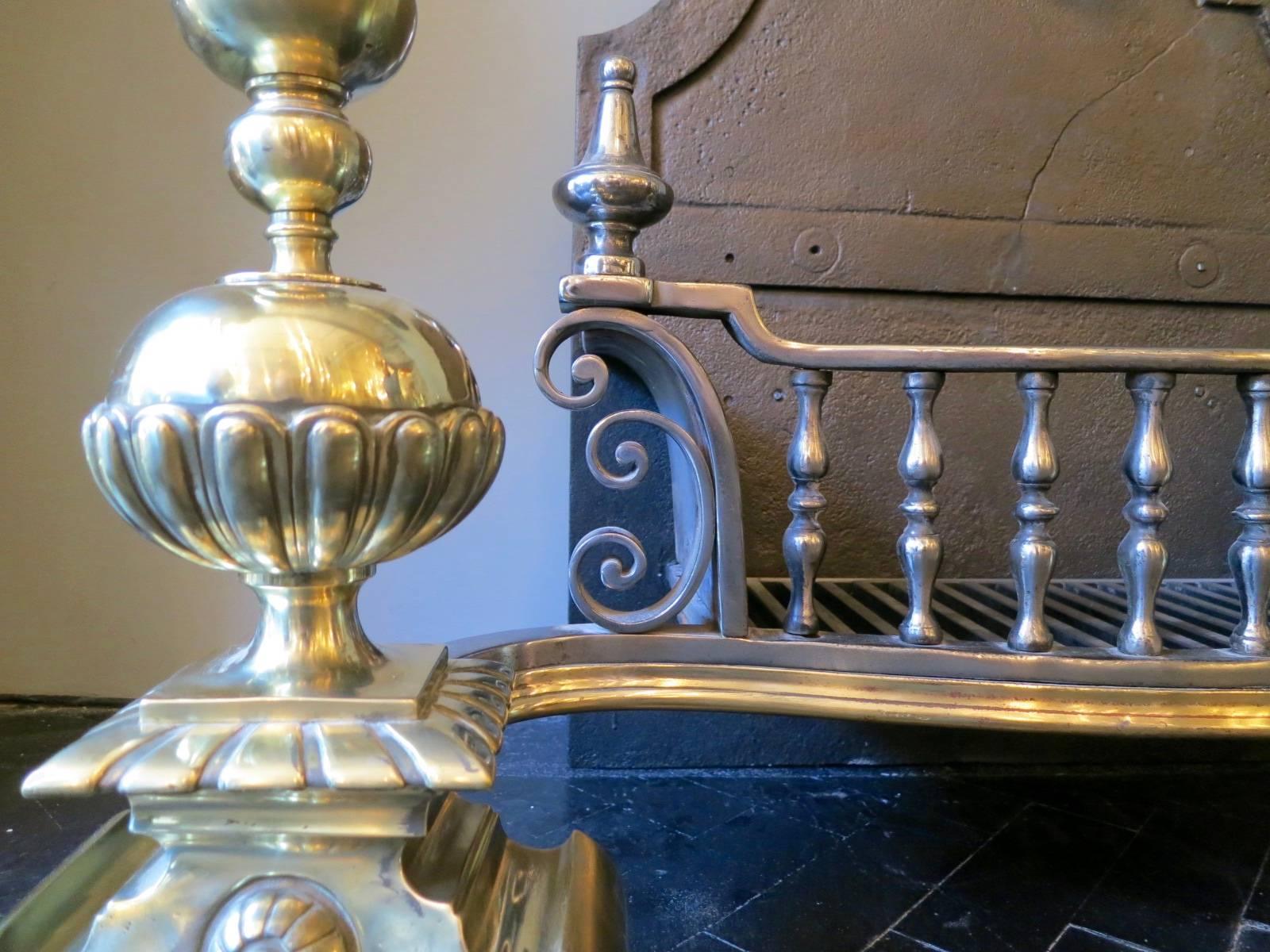 A substantial and imposing grate from the Victorian period, with large gadrooned brass ball finials. The burning area having balustrade bars flanked by scrolls and steel finials. A quality piece with shaped cast iron fire back.
