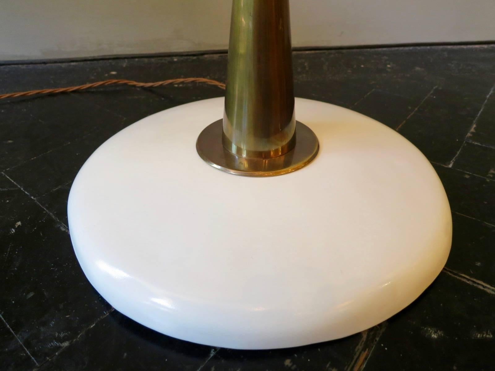 A tall 1950s Italian floor lamp in brass with white lacquered base and black shade, with swinging and pivotable movement. A very good quality piece and fantastic example of Italian modernism.