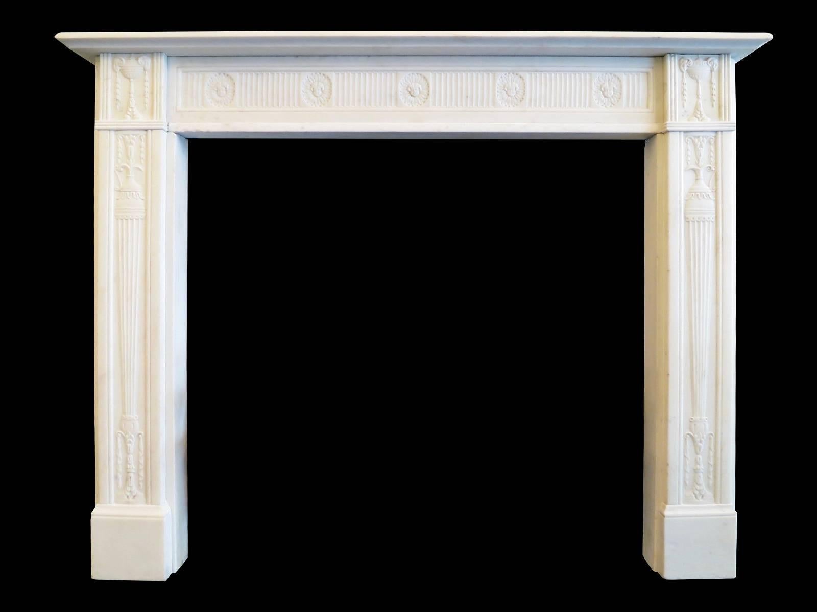A very fine and well proportioned mantel in Statuary white marble. The jambs having carved tapering pedestals, bell drops and drapery. The corner blocks of classical ram's head urns again with descending bell drops, flanking a running carved bow