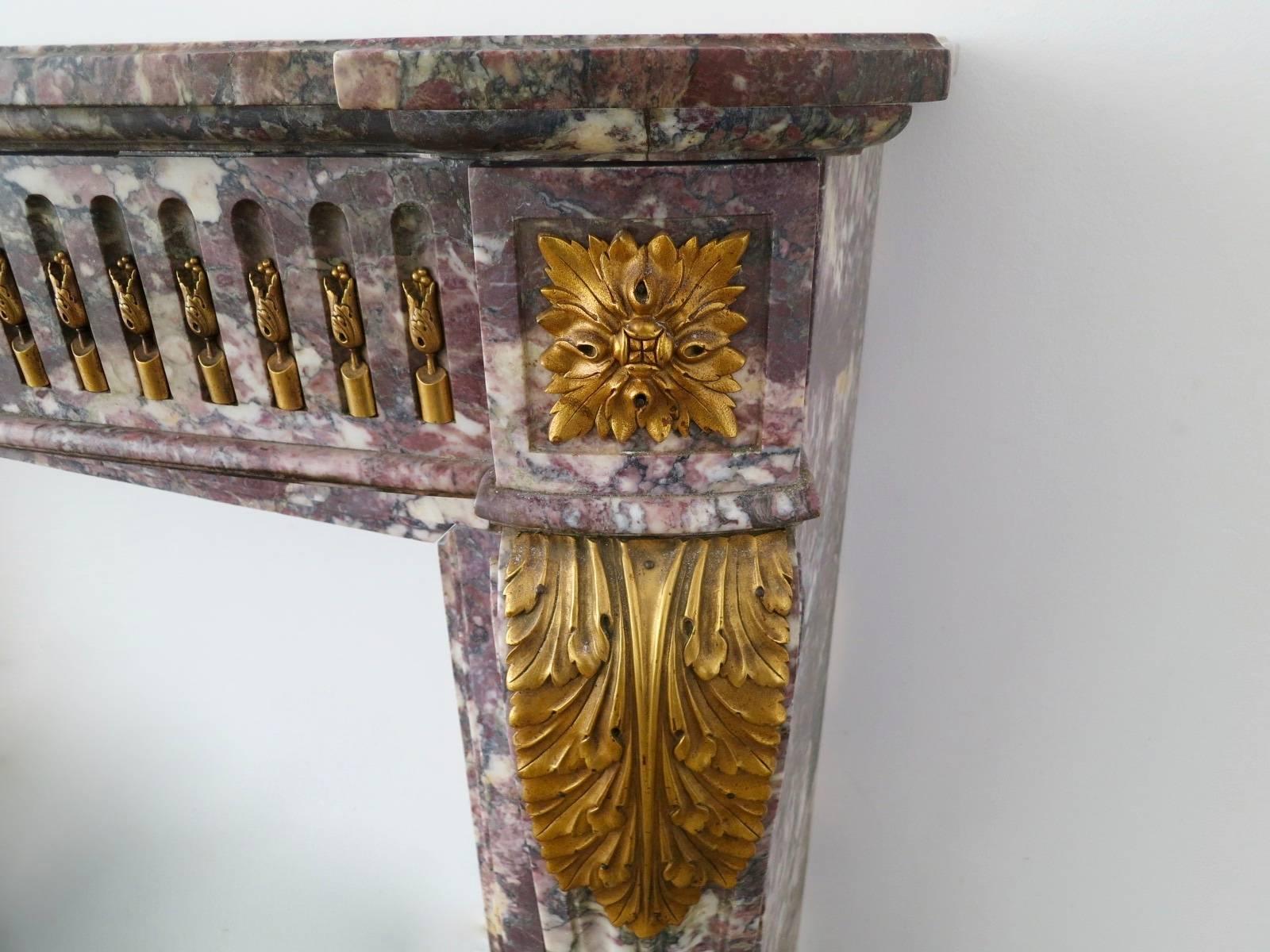 A large French Louis XVI style mantel in superior quality and highly variegated Breche Violette marble. The cantered jambs with acanthus leaf and square Paterae ormolu adornment. The wide bow fronted frieze with stop flutes and again richly