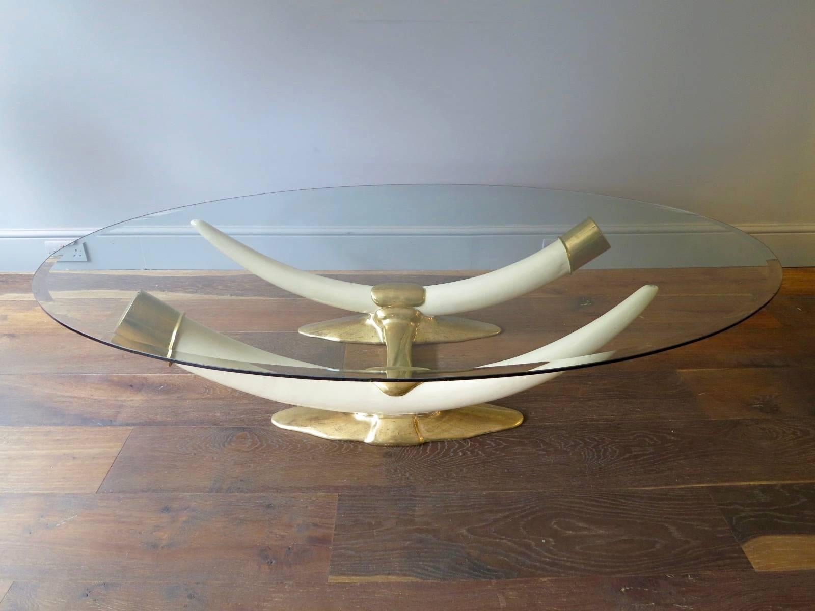 A rare and signed coffee table by Duval-Brasseur, with gilt bronze base, resin faux tusks and oval shaped glass top.