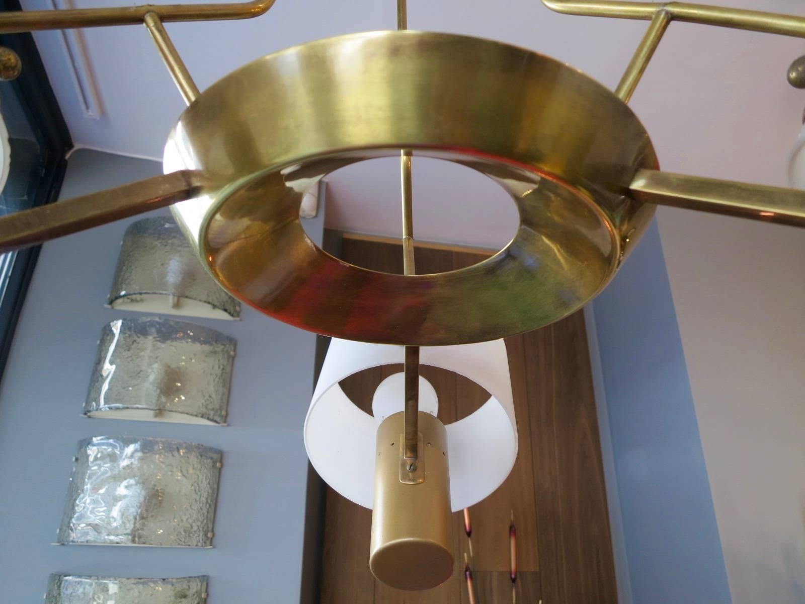 A brass pendant light, with three arms and drum shaped opaque glass light diffusers. Attributed to Stilnovo.
