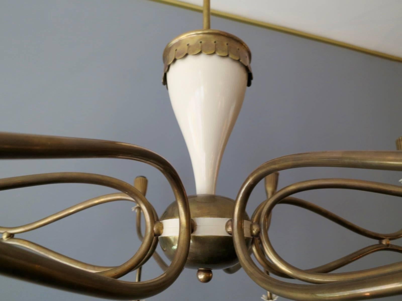 A large sixteen arm chandelier in brass with cream lacquered accents. The reeded bulb holders capped with cream petal shaped decoration, facing both up and down. The centre in brass and cream lacquered body. A very good quality piece in superb