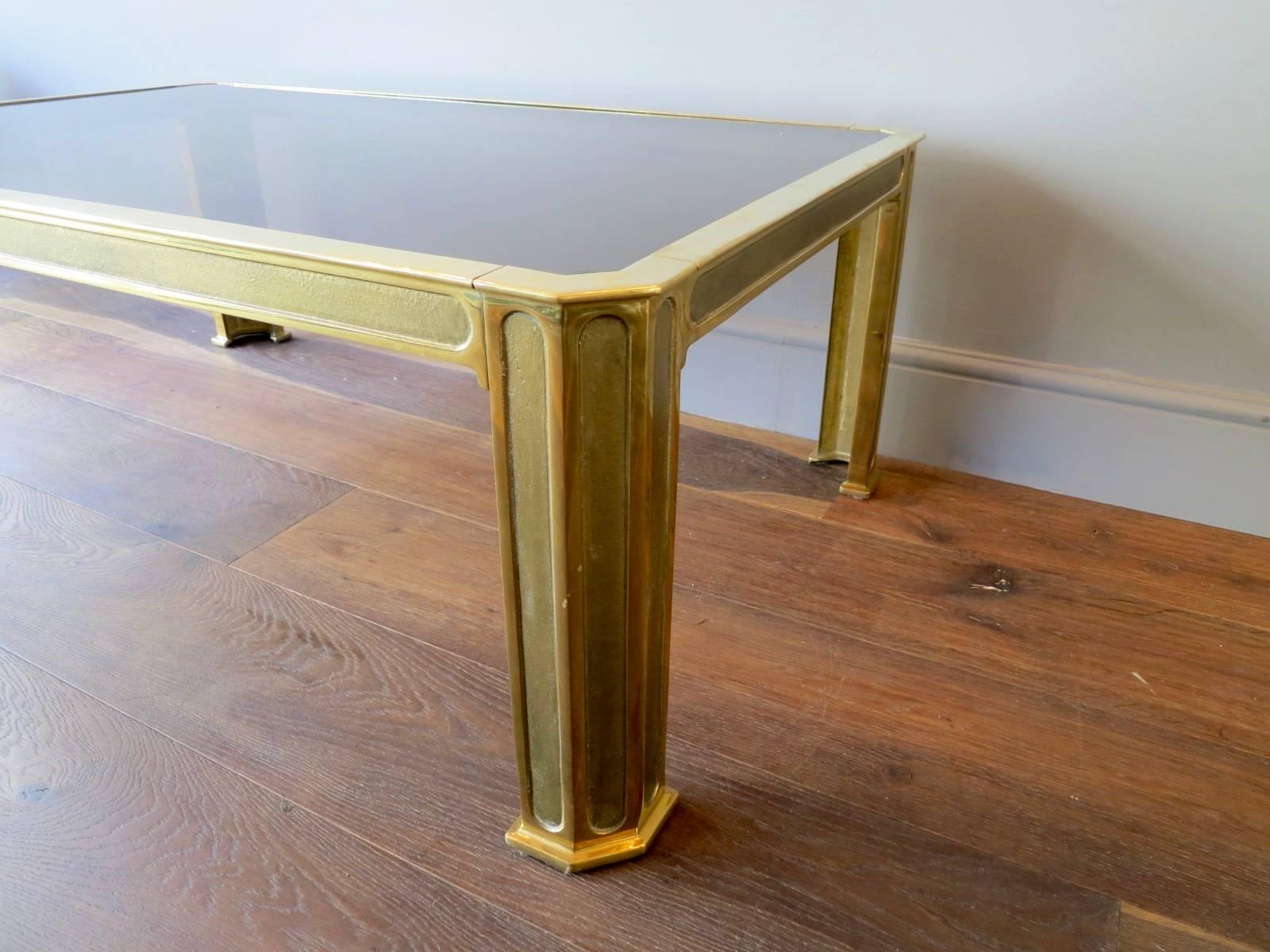 A large coffee table in cast brass with thick smoked glass top, in the style of European designer Peter Ghyczy.
