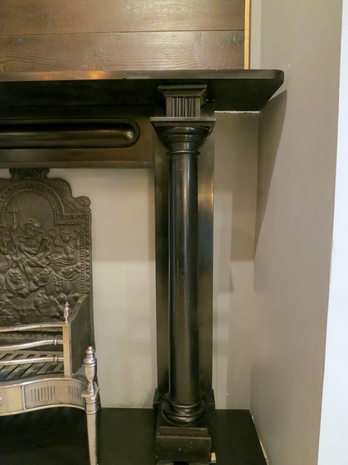 A substantial and superior quality chimney piece in black Irish Kilkenny marble, early 19th century Regency period fireplace, with fully detached columns supported on square footblocks, surmounted by square fluted cornerbacks. The frieze with a