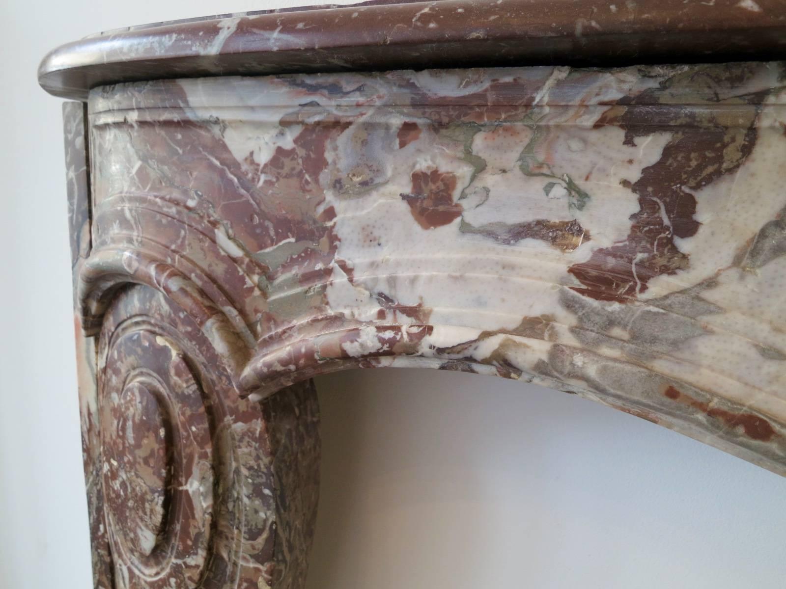 An unusual French fireplace in Rouge Royal marble, in the manner of Louis XV with a serpentine moulded frieze which is supported by inverted cantered jambs with scrolled carving detail to front, mid-late 18th century. 

Measures: Opening 113cm W x