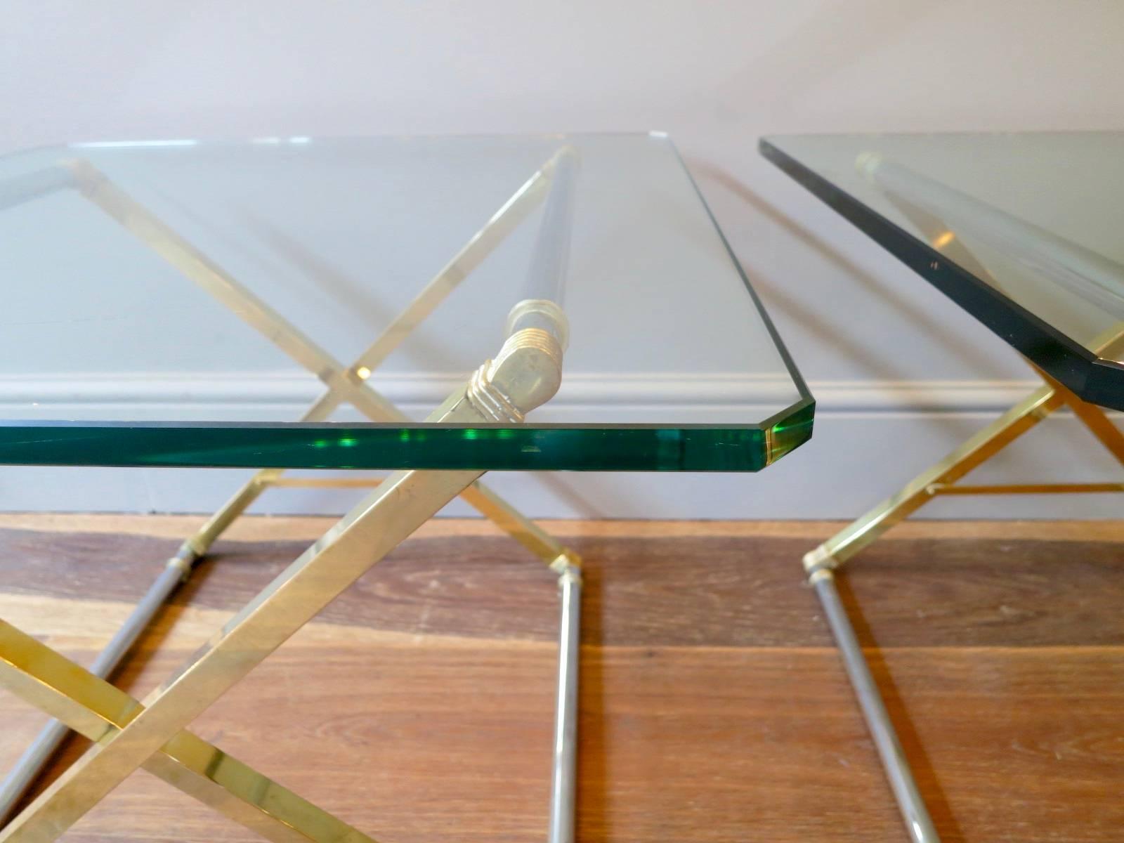 A pair of matched end tables or side tables by designer Peter Ghyczy, the brass and chrome adjustable X frame tables topped with thick edged glass tops.