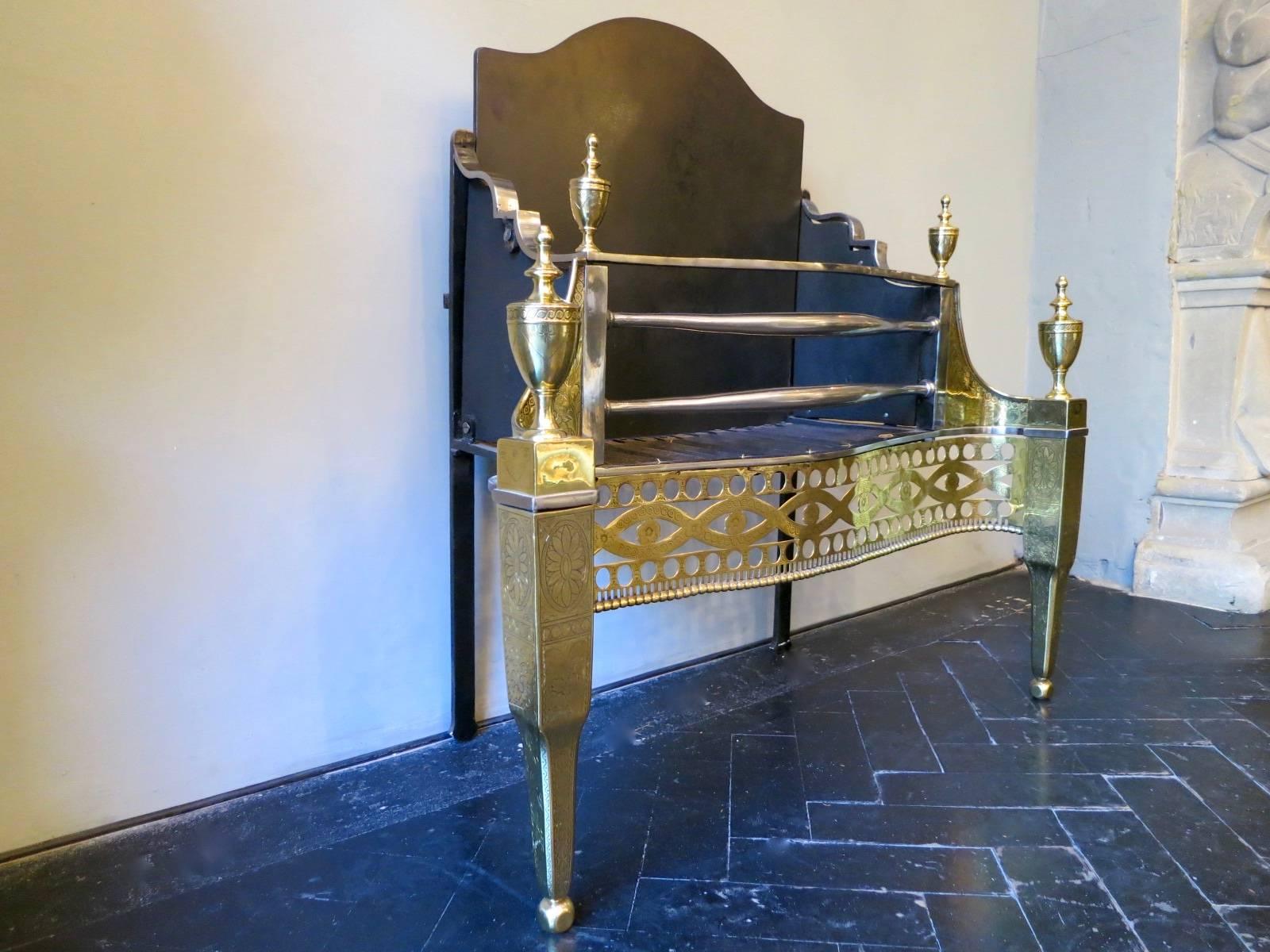 A 19th century Irish fire grate, with geometric pierced fretwork flanked by engraved columned ball footed supports. The supports and burning area capped by engraved classical urn finials, with engraved wings. Having polished steel bowed fronted