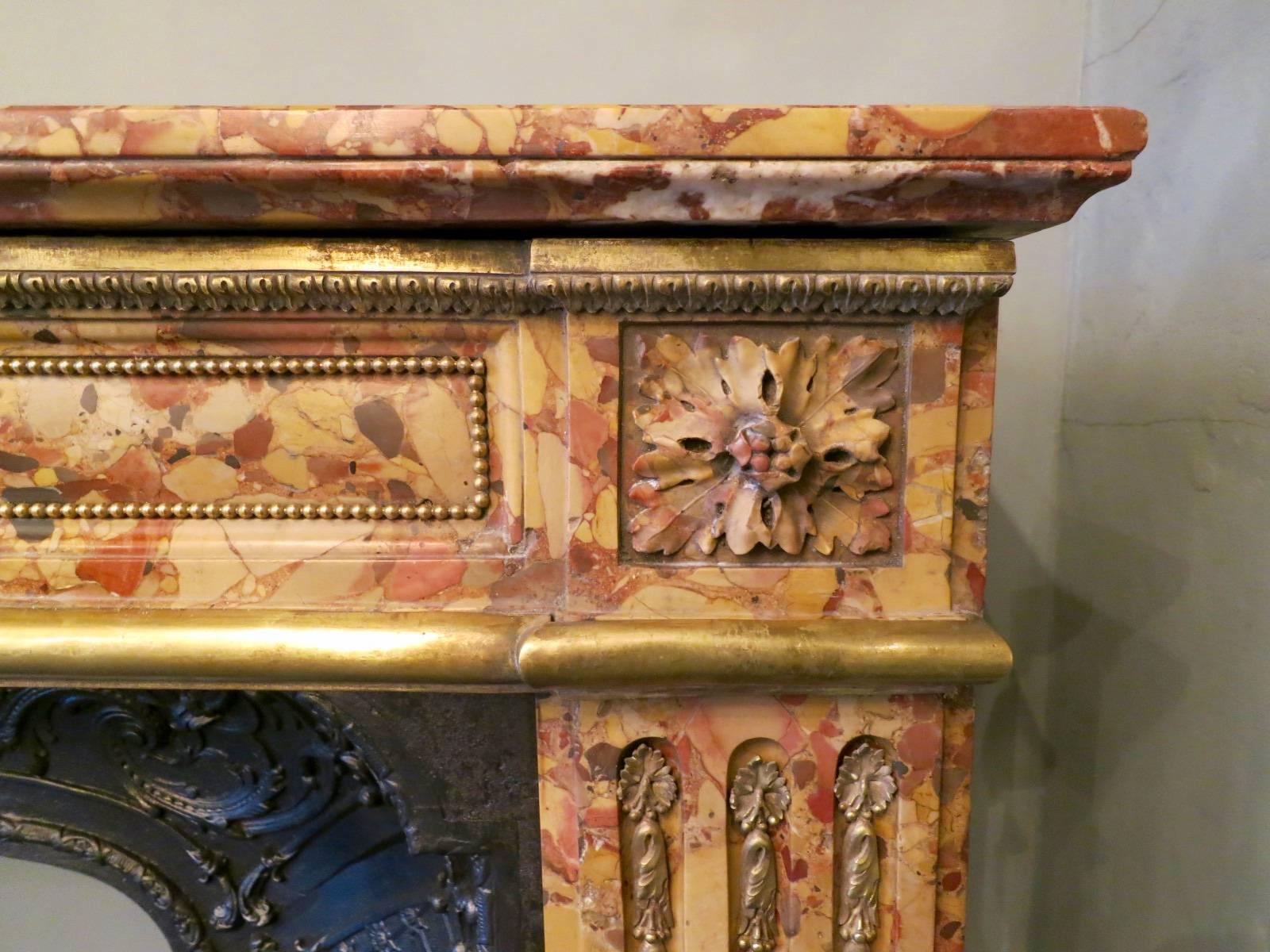 A Louis XVI period late 18th century fireplace in Breche d'Alep marble with Ormolu enrichments and cast iron interior panel. The frieze with beaded decoration, acanthus leaf and moulded trim witch conforms with the foot block mounts. The Jambs