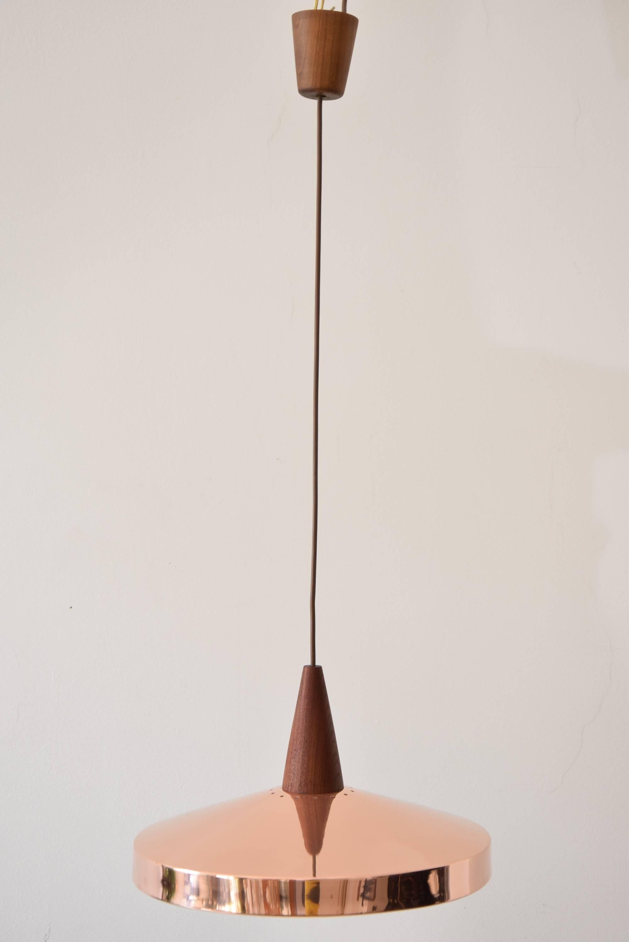 Elegant hanging lamp of copper and teak wood, circa 1960s.
Polished and stove enameled.
The height of the chandelier is easily adjustable to fit different rooms.