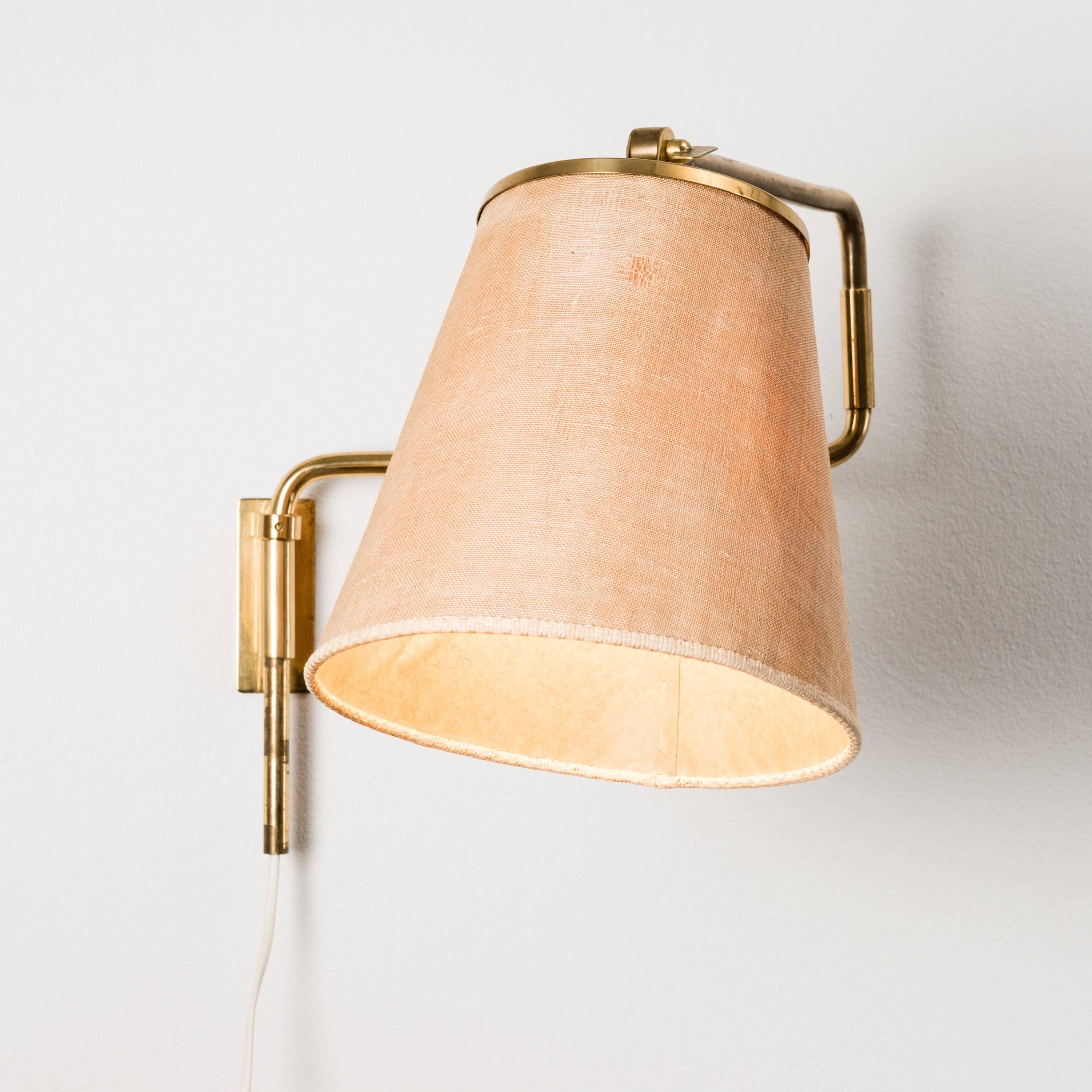 Paavo Tynell, wall light, model 9414, Taito, adjustable brass arm, with manufacturer's mark. Measure: Length ca 70 cm, height of the lampshade ca 22 cm.
