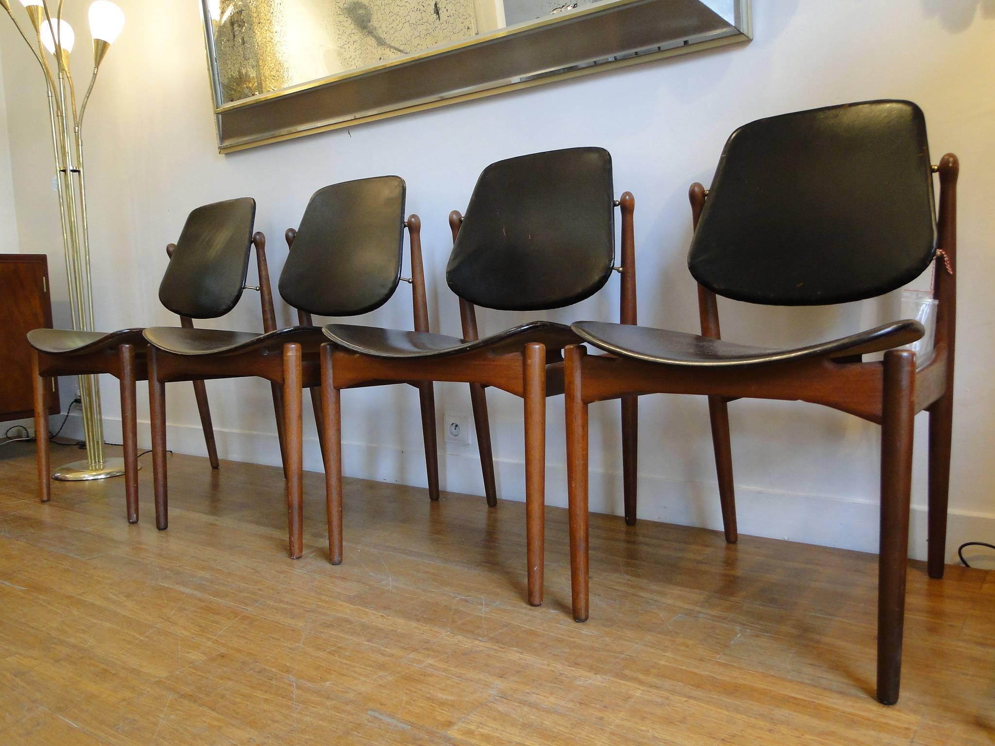 Arne Vodder Danish modern solid teak dining chairs made by France and Son of Denmark from 1957. Markers label with brass medallions and embossed insignia. The tilting black leather backs cradle the body for a very comfortable seating position. 
One
