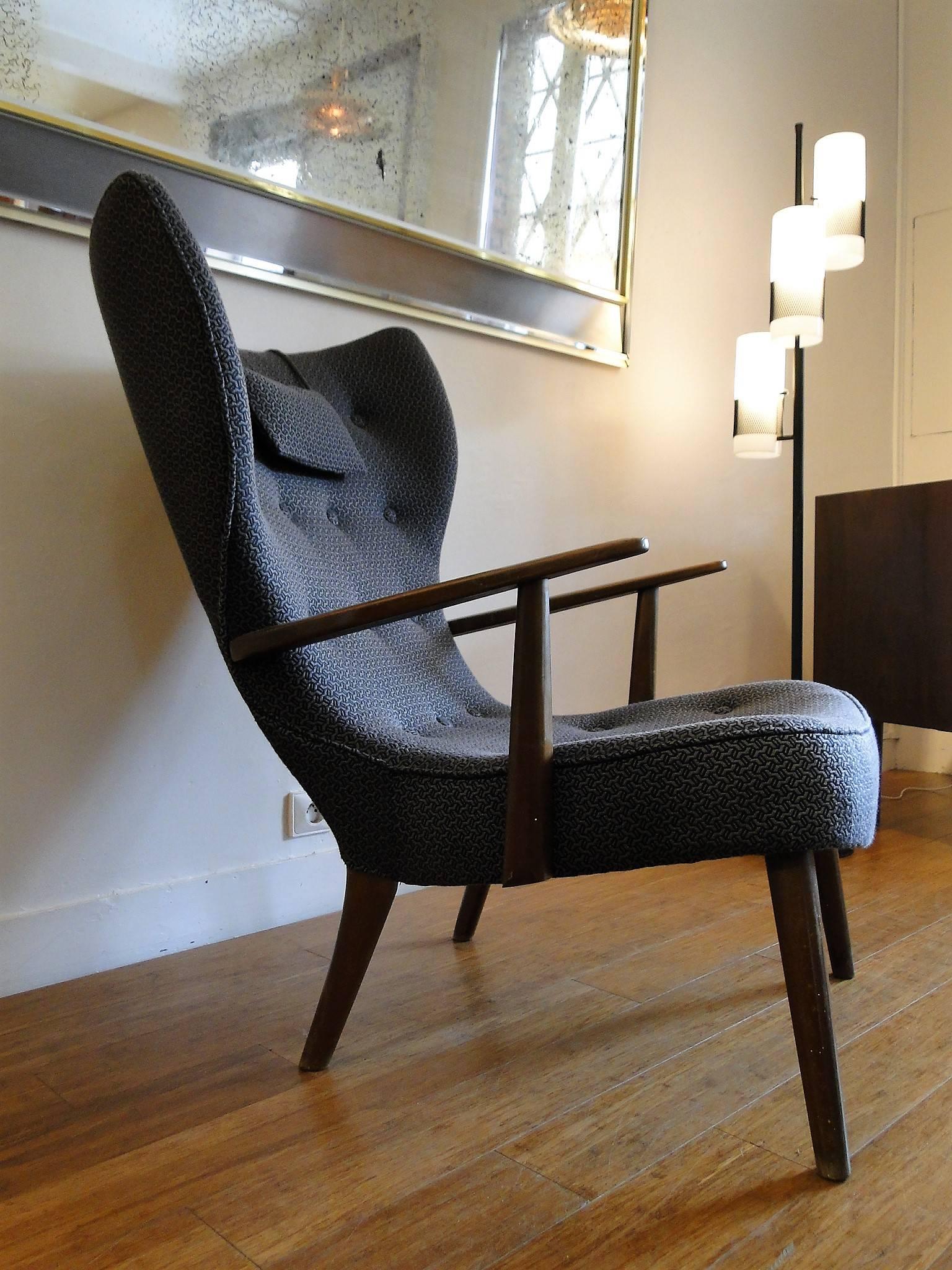 A lounge chair by Acton Schubell and Ib Madsen with legs of stained beech, upholstered in black with covered buttons.
 