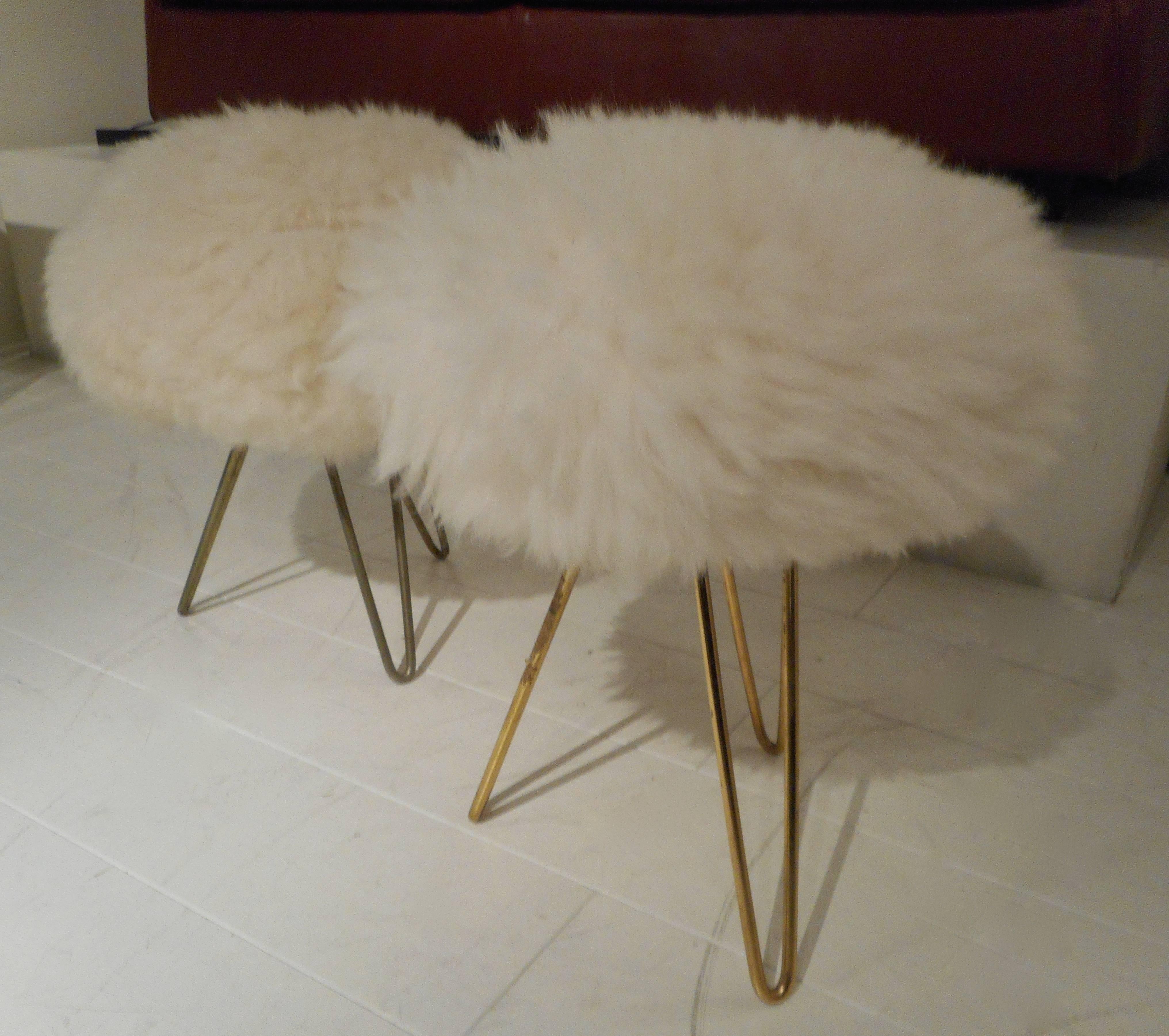 Pair of 1950s ottomans in the style of Jean Royère. Brass feet and fur sits.
  