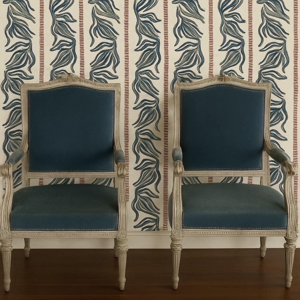 Elegante pareja de sillones franceses de finales del siglo XIX que encarnan la gracia intemporal de la época de Luis XVI, con armazones pintados bellamente envejecidos, barandillas de cresta duramente talladas, patas neoclásicas estriadas y brazos