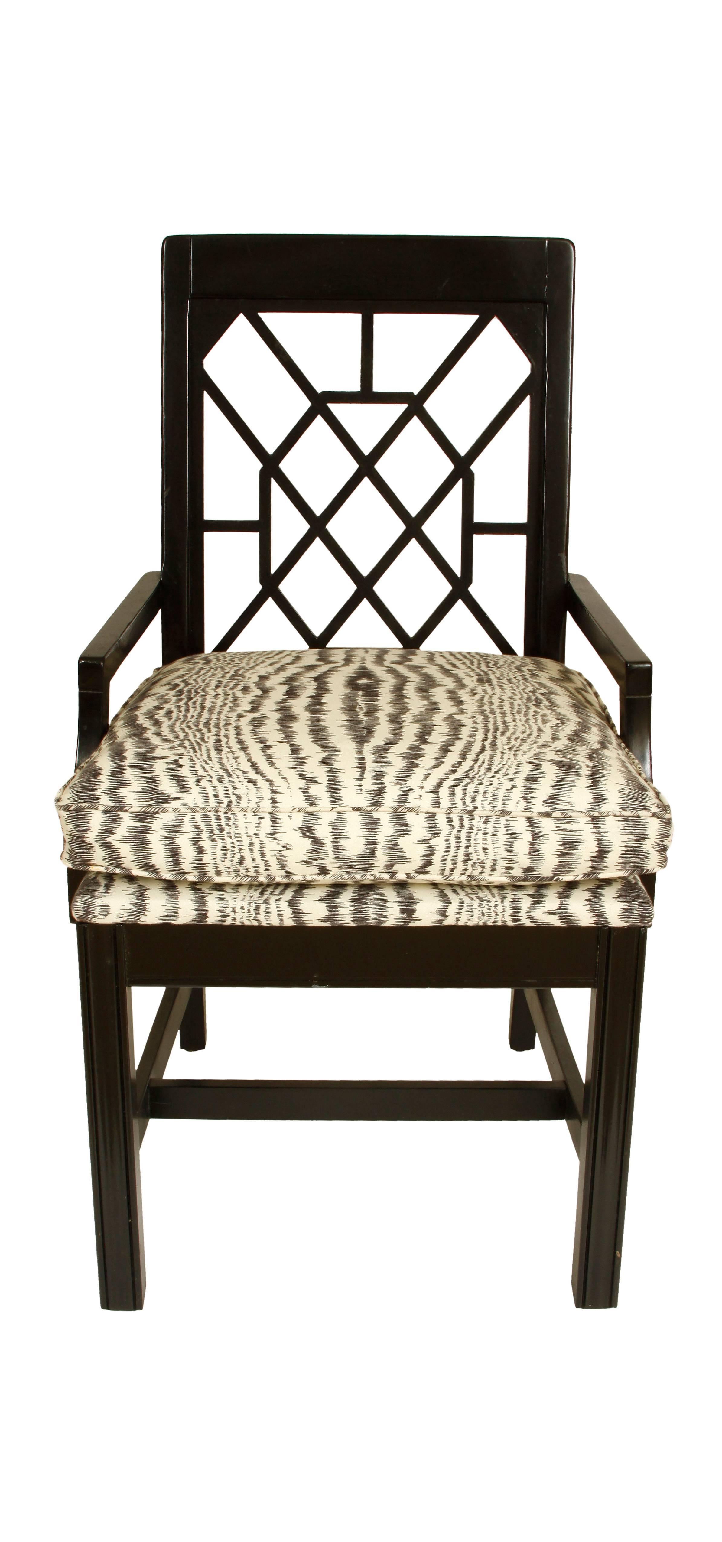 A pair of black painted fretwork chairs with faux bois fabric attached cushions.