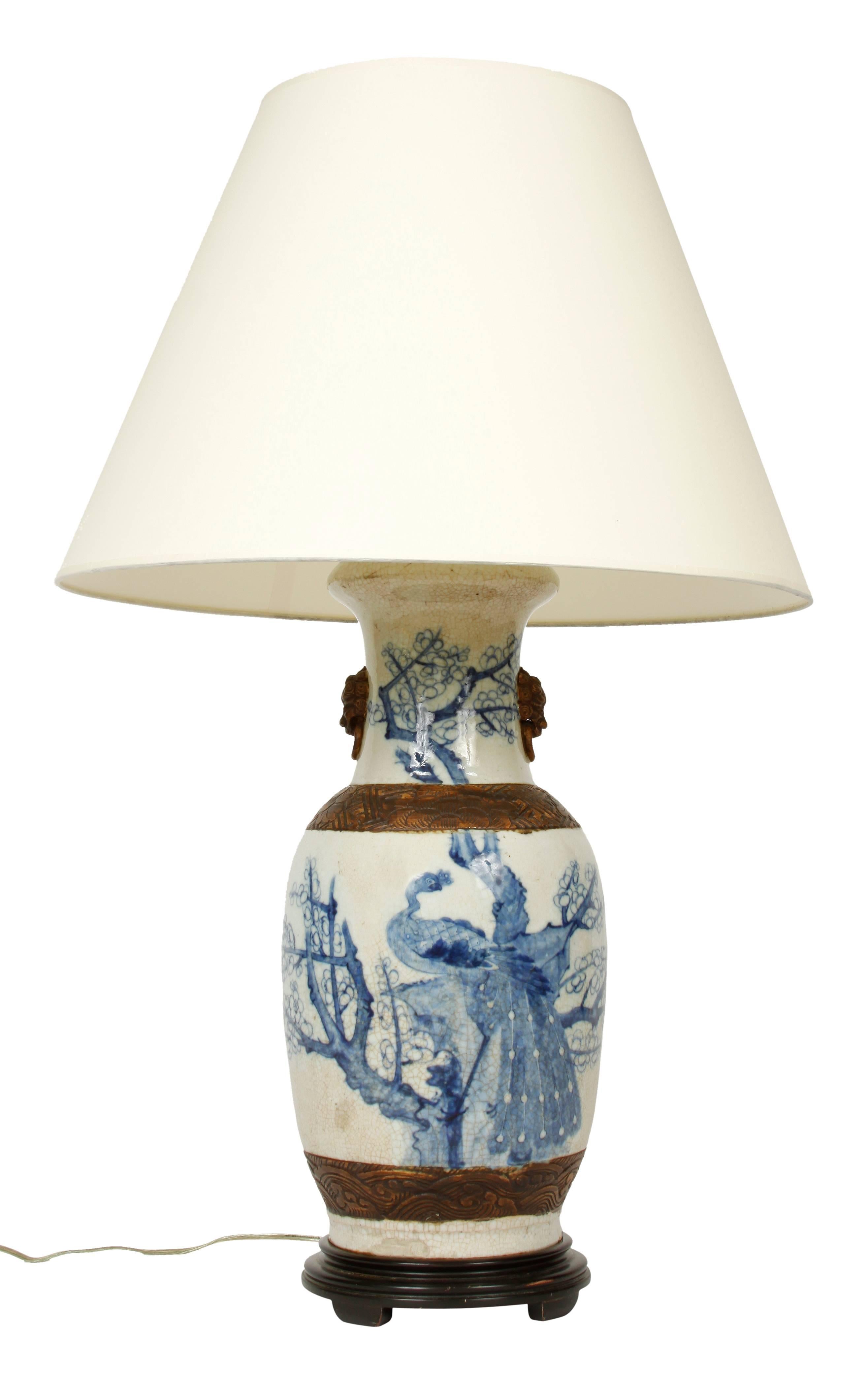 A pair of vintage Chinese export lamps. Porcelain lamps with metal details on wooden bases. Similar motifs of peacocks and flowers; each lamp is hand-painted and the design differs slightly.
 