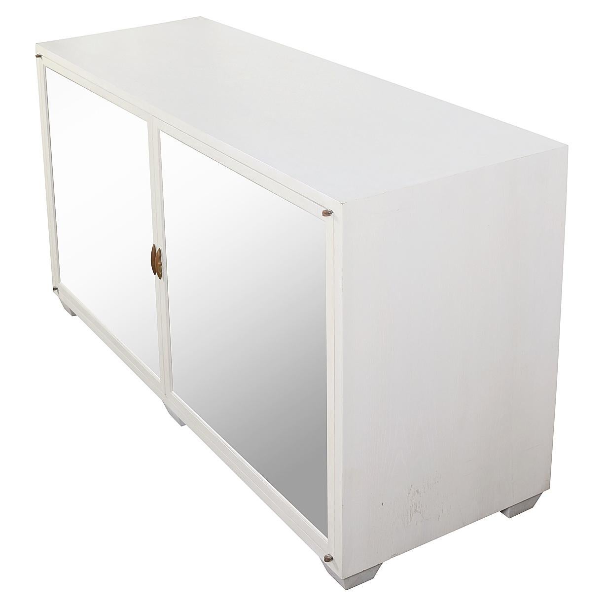 A striking white painted wood sideboard by Julian Chichester, blending classic elegance with contemporary flair. The piece features two mirror-front doors, which reflect light and add a touch of glamour, while subtly enhancing the sense of space in