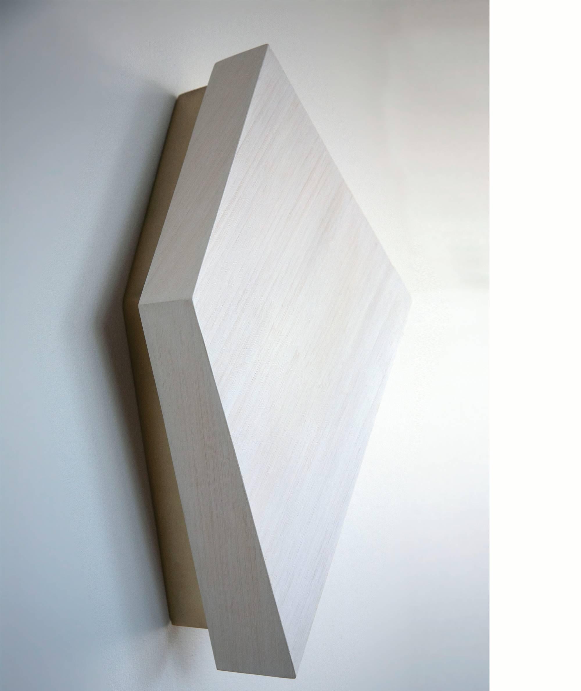 This geometric, wall-mounted sconce appears to go from solid object when off, to glowing wall washer when on. These can be mounted in any direction around the central mounting point. They stand alone on a wall, in pairs, or groups. Arranging them