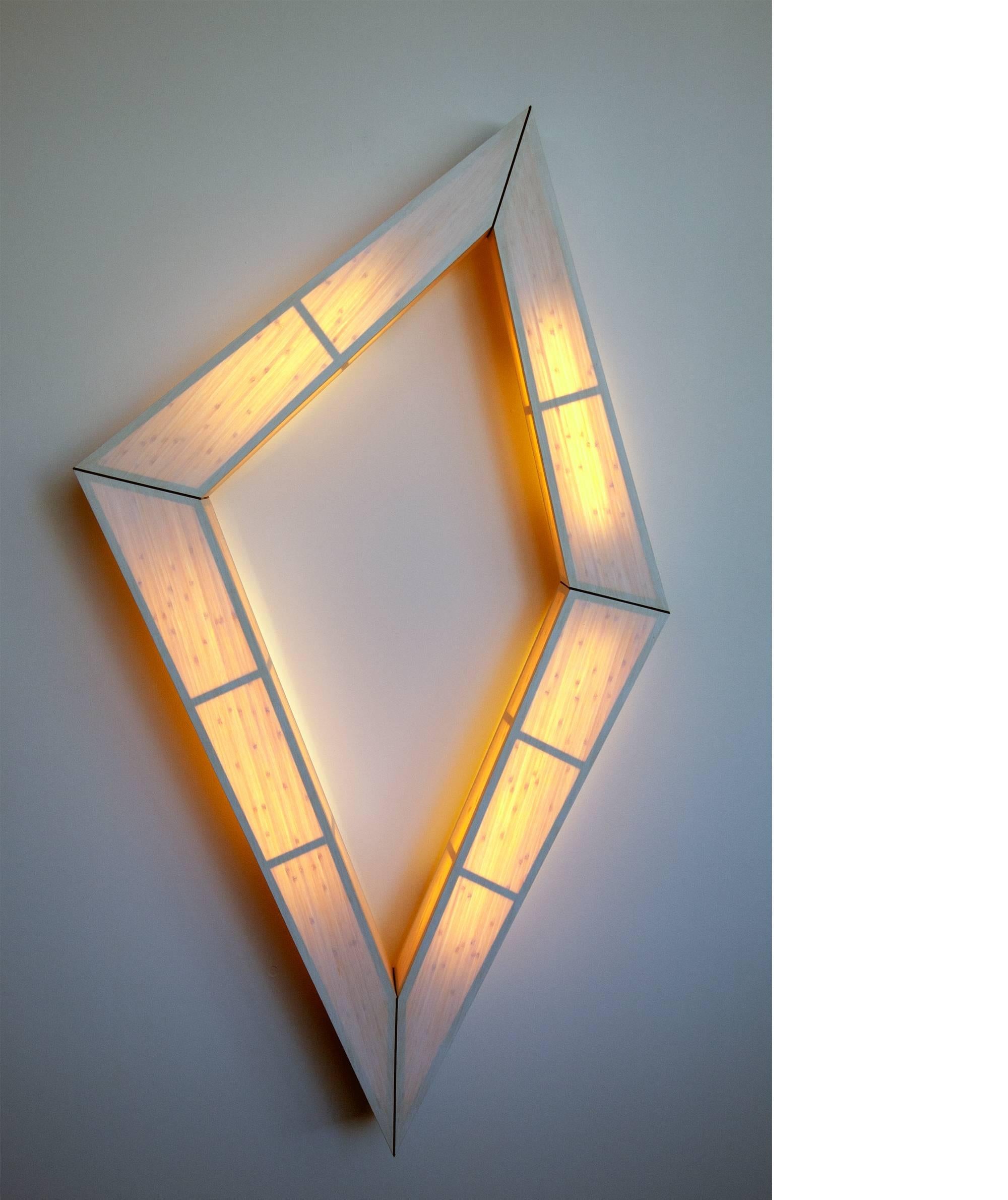 This large wall-mounted lighting piece defies expectation. It appears as solid sculptural object when off and elegantly transforms into a floating light-body when switched on. In the central open area you can specify a mirror as an optional add-on.