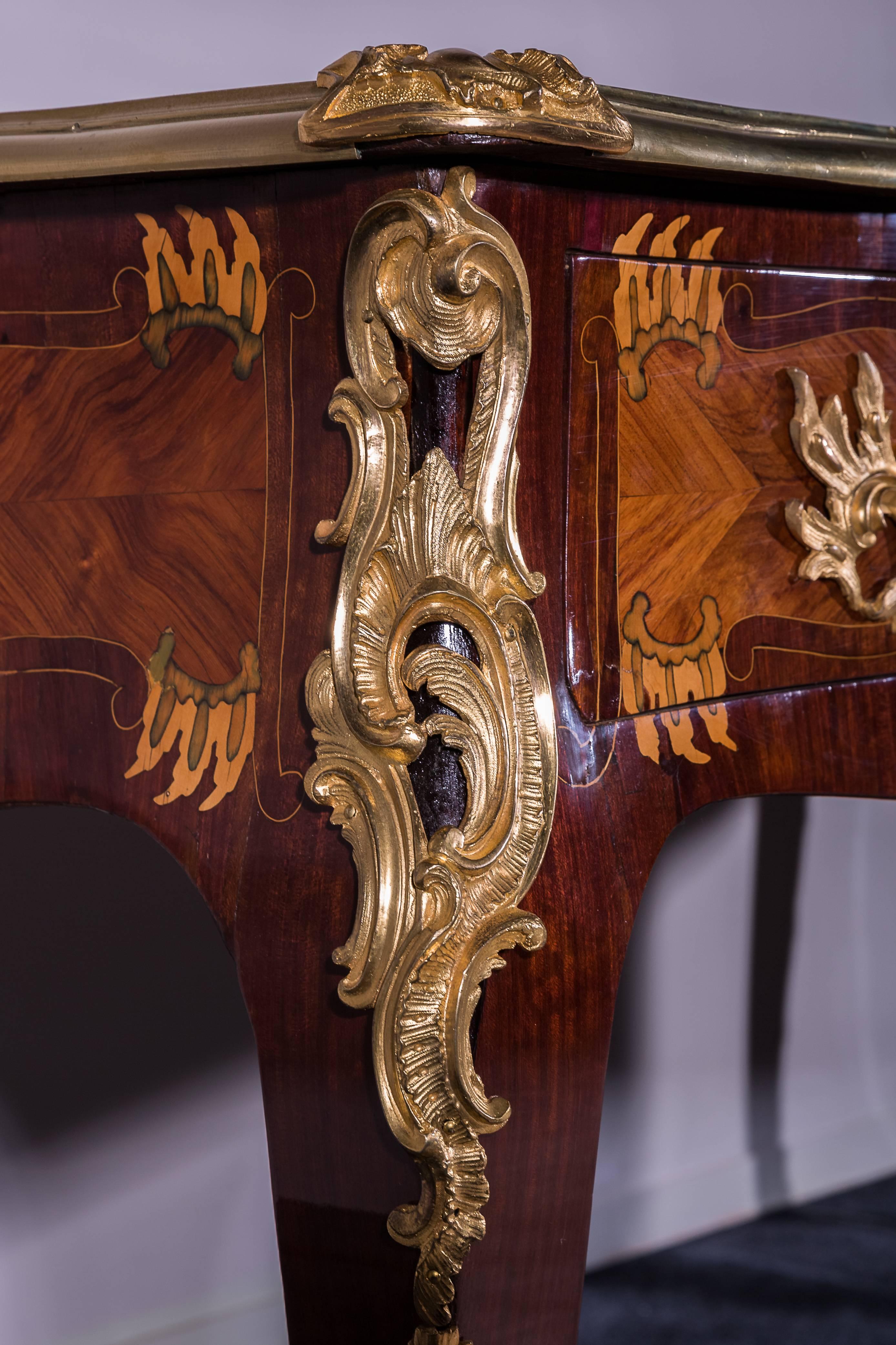 Great desk inlaid with amaranth and tulipwood. Its belt opens with three drawers ornamented with gilt bronze. Its top is covered with leather and lined with gilt bronze. This desk is ornamented with chiselled and gilt bronze. Its marquetry is made