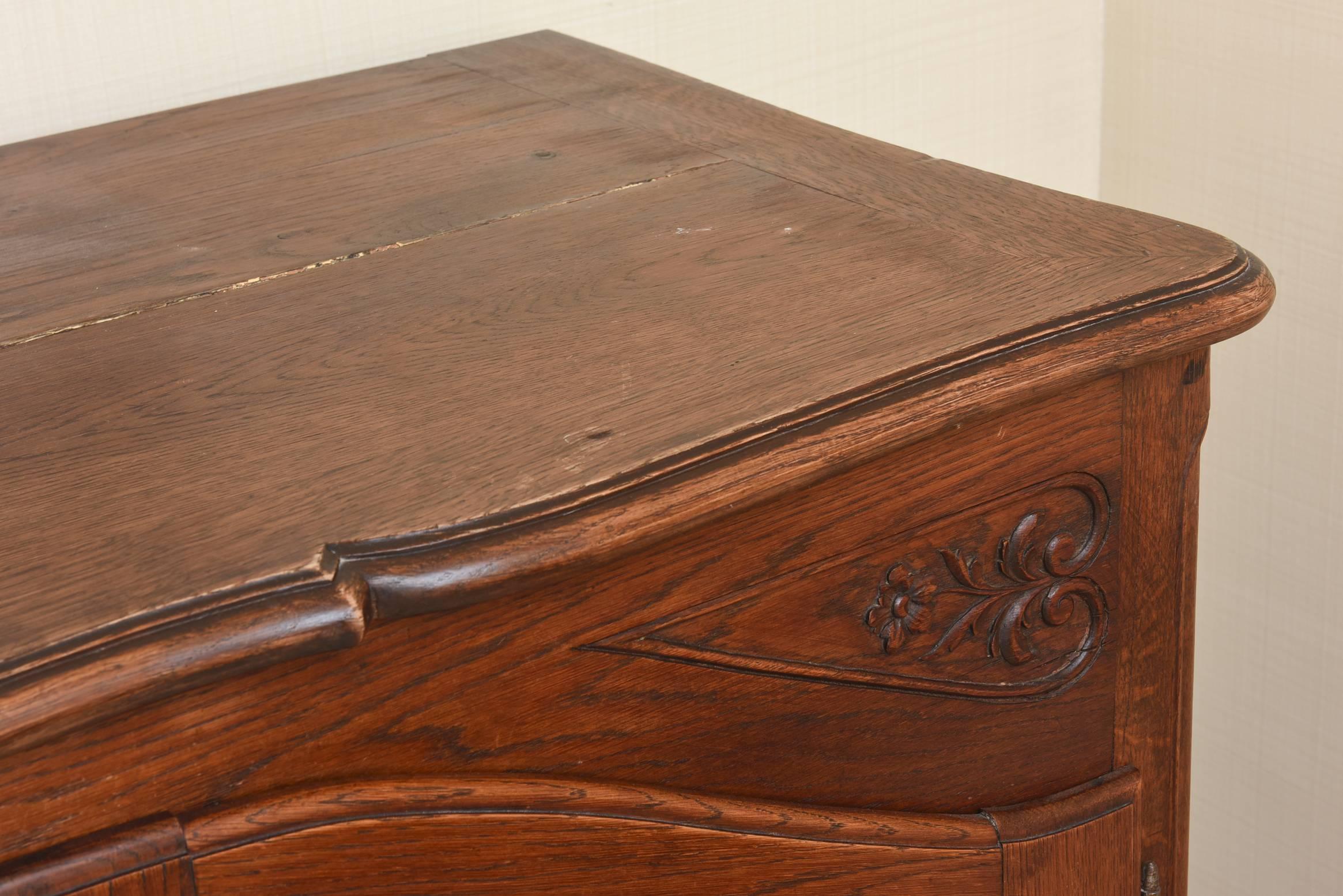 The rectangular top over an arched open shelf over two short drawers flanked by cabinet doors; carved with floral roundels; on scroll form feet.