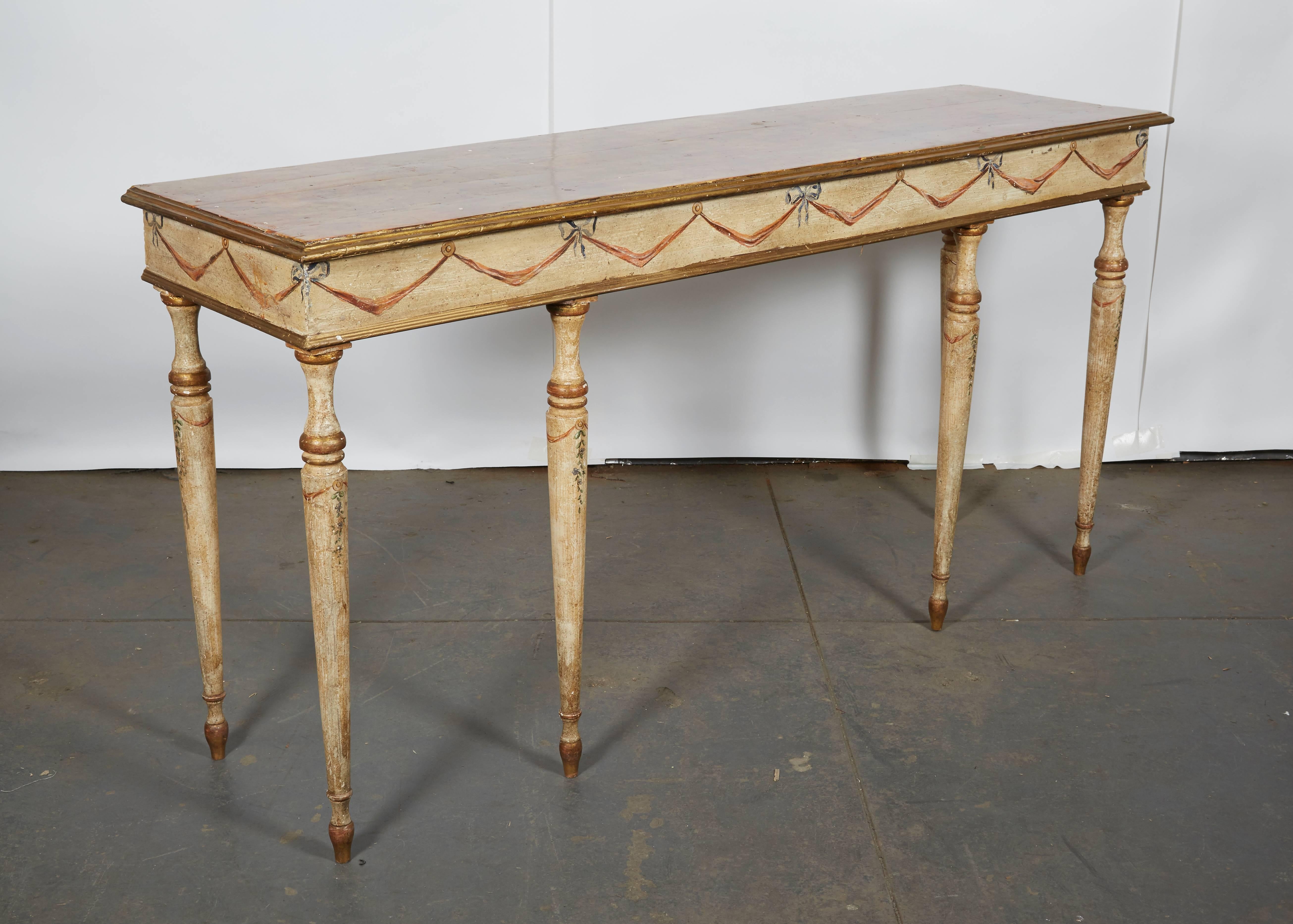 Charming neoclassical table with red faux marble-painted top with gilt moldings over an ivory-ground table with ribbon-tied swag decoration on the frieze and floral garlands on the legs.