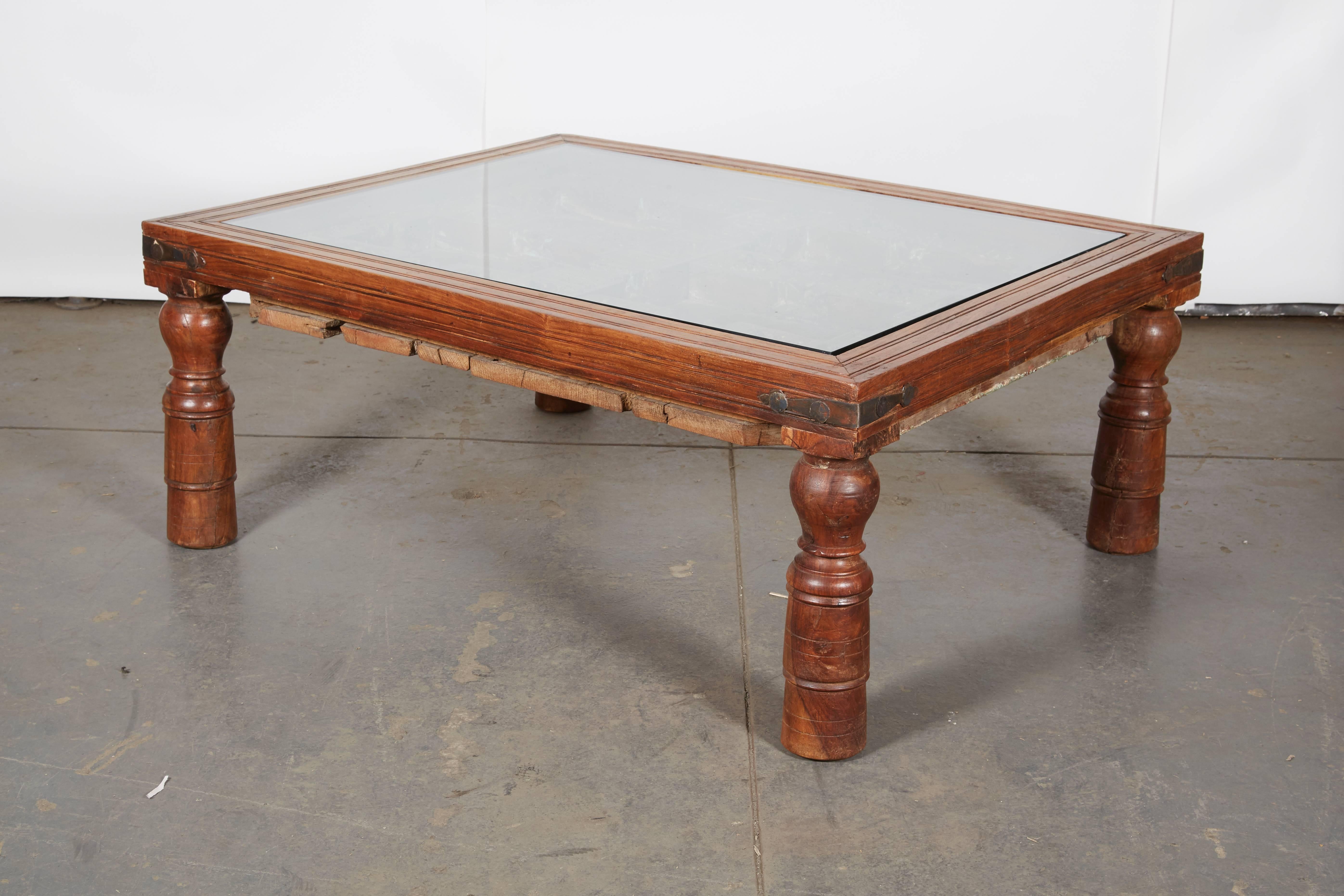 The nearly square top incorporating an antique Indian carved door with clear glass set above.