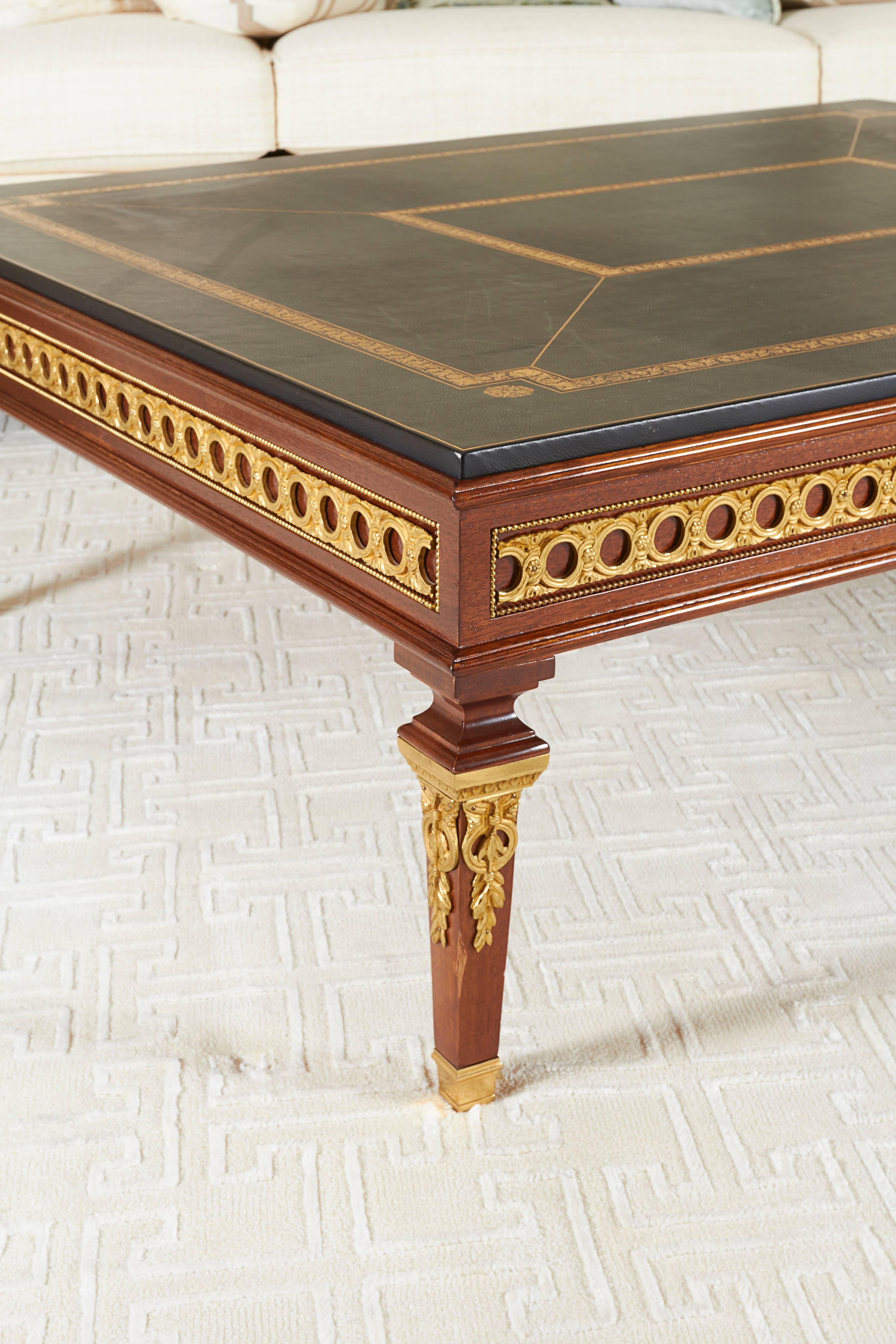 The nearly square top lined with black gilt-tooled leather over a paneled frieze mounted with guilloche ormolu; raised on square tapering legs terminating in sabots.