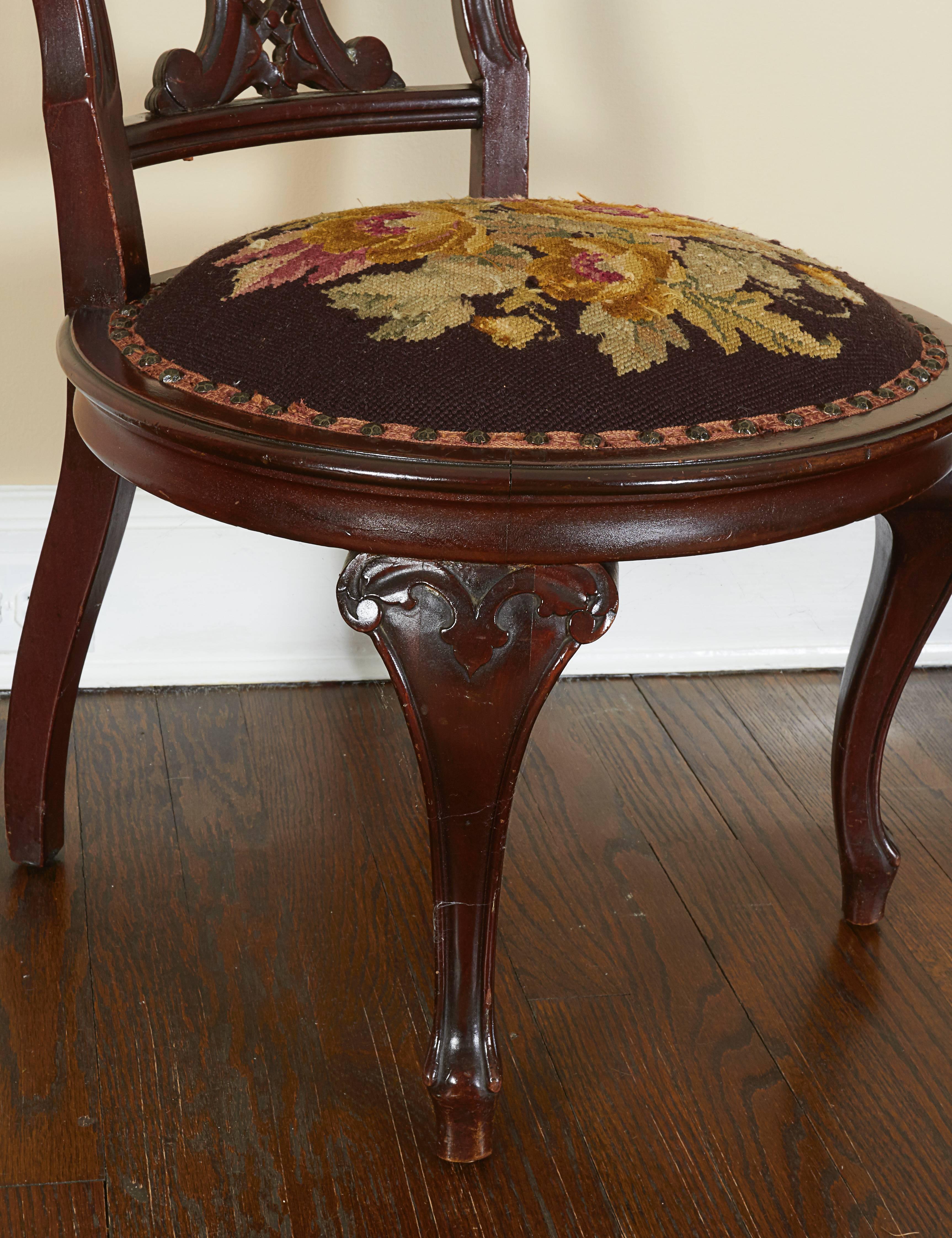 The back with elaborately pierced foliate back splat, the round floral needlework-upholstered seat raised on cabriole legs ending in pad feet on plinths. Sits low to the ground.