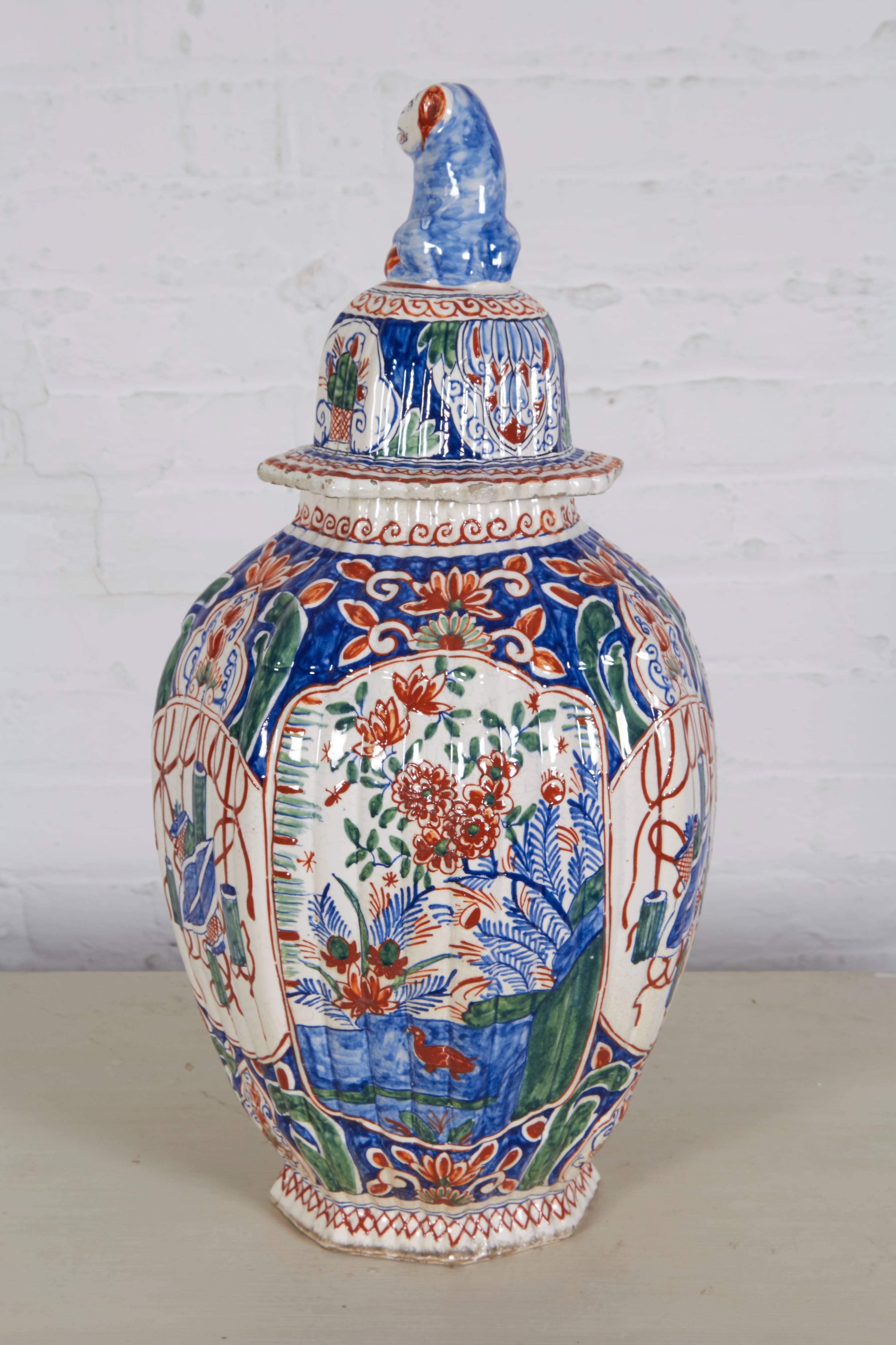 Of ribbed globular form decorated with panels of birds and floral sprays alternating with ceremonial vessels; surmounted by a lid with dog finial. With extensive markings to underside.