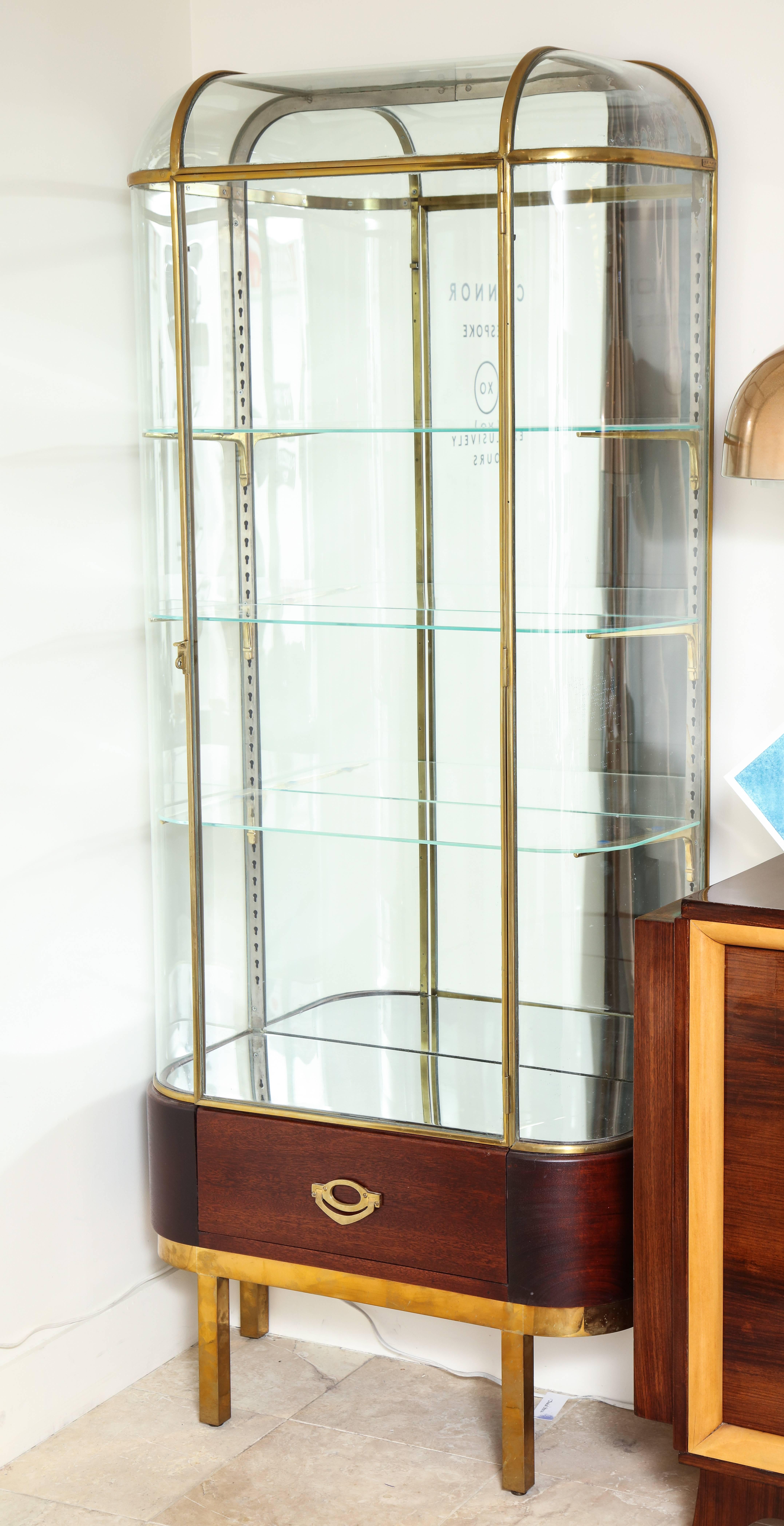 Fitted with three adjustable glass shelves on a mahogany base with drawer; now on a later gold-lacquered metal base supplied by Barneys New York. Acquired in France by Barneys New York. The smaller one measures 36.25 wide.