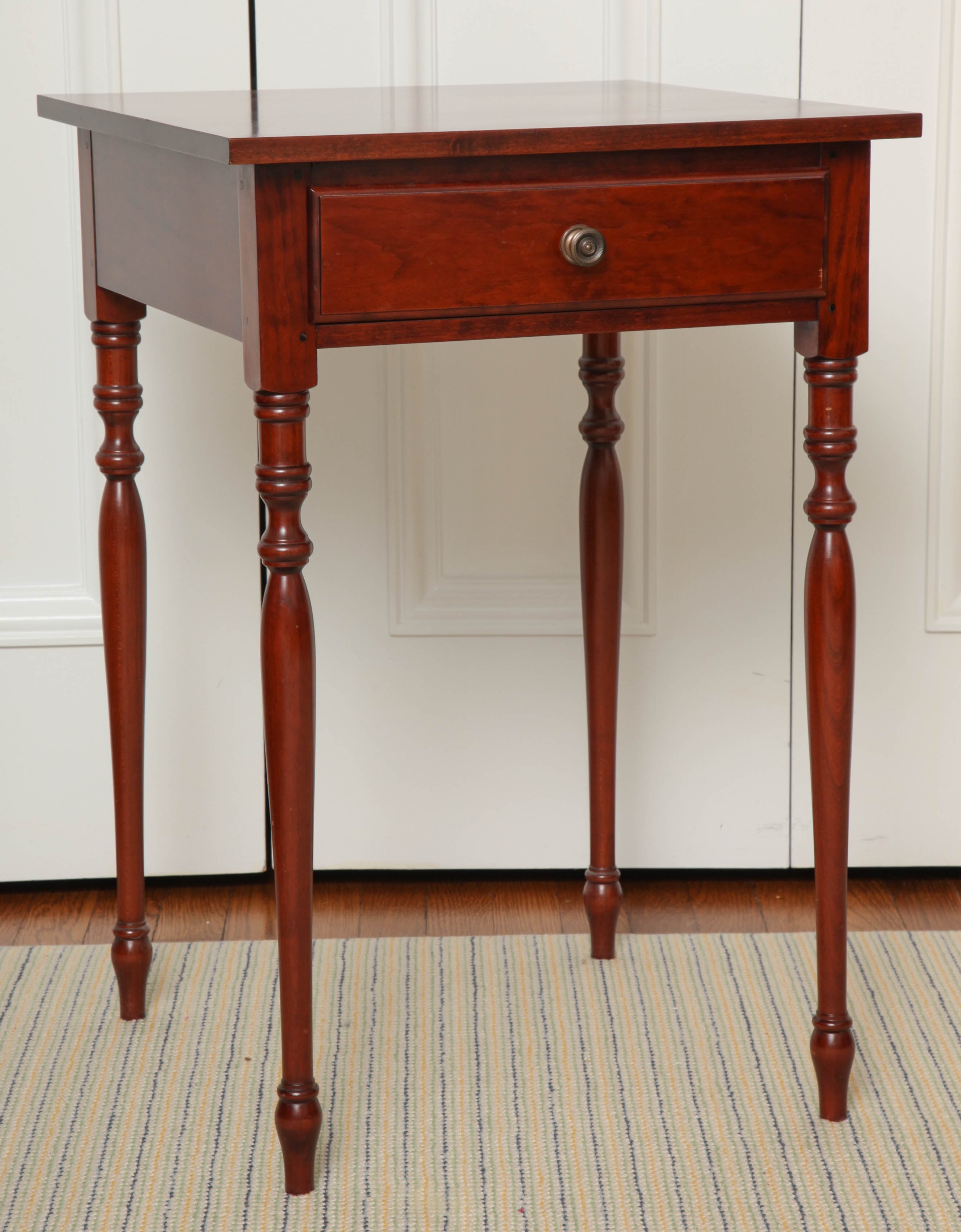 The square top over a frieze drawer, raised on turned and tapering legs. Two available.