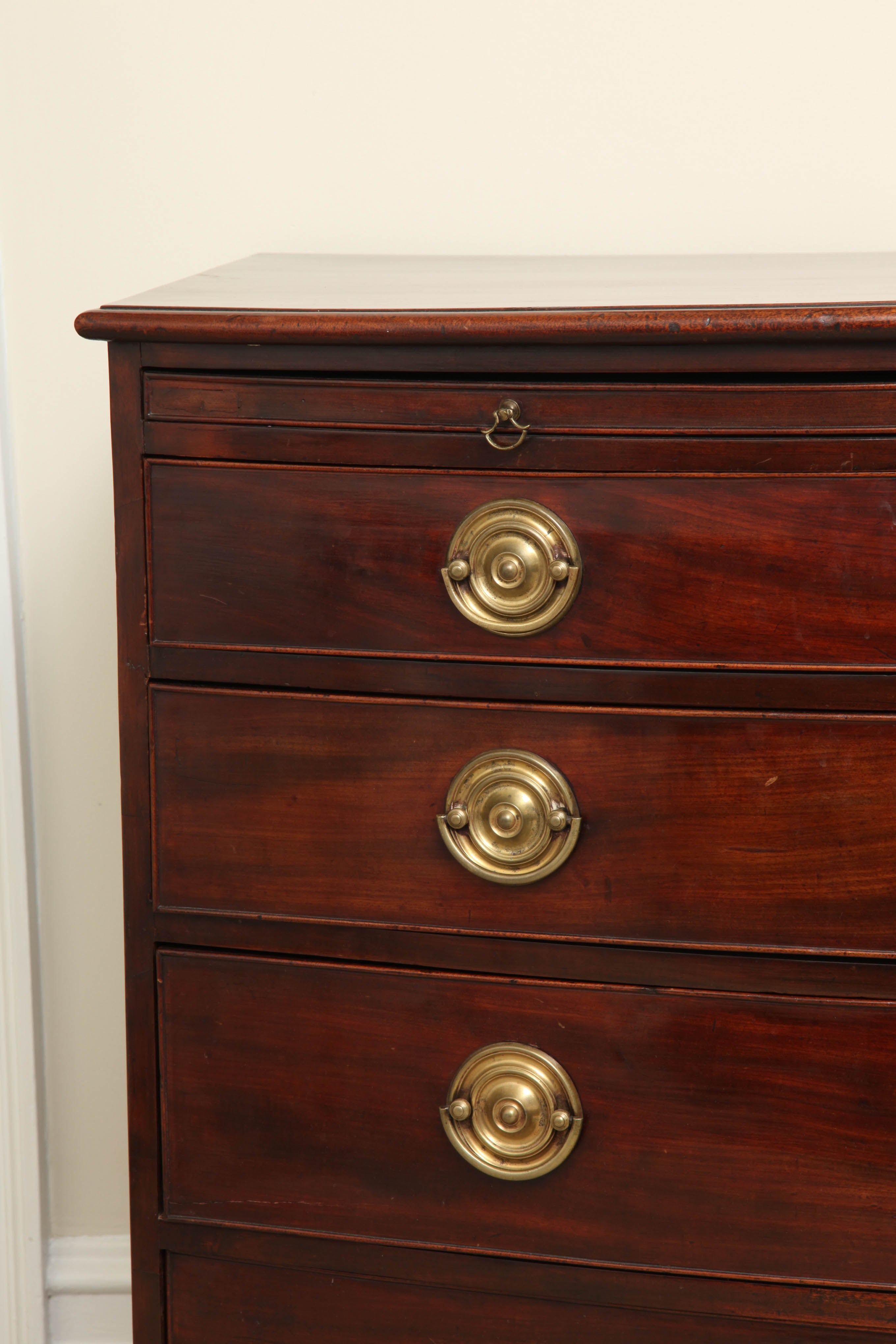 With deep rich color and lively figure; the fitted with a brushing slide over four graduated, cockbeaded drawers with brass pulls, above the scalloped apron and outswept feet.