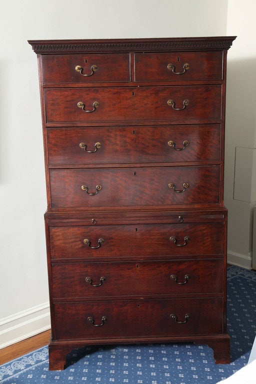 Very handsome piece featuring a rich, glowing original surface and original brass hardware. The upper part with overhanging cornice enriched with fretwork carving, over two short and three graduate cockbeaded drawers; the lower part fitted with a