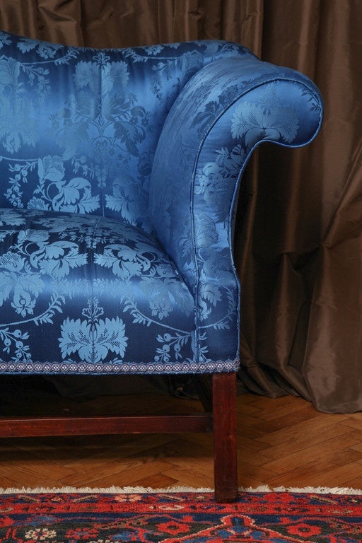 With silk damask-upholstered serpentine back, outward scrolling arms and seat; raised on square legs joined by stretchers; on casters. 