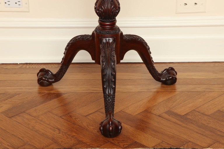 The octagonal tilt-top surmounted by a conforming gallery, raised on a baluster columnar support finely carved with stop-fluting and acanthus leaf decoration, on three cabriole legs terminating in ball and claw feet.