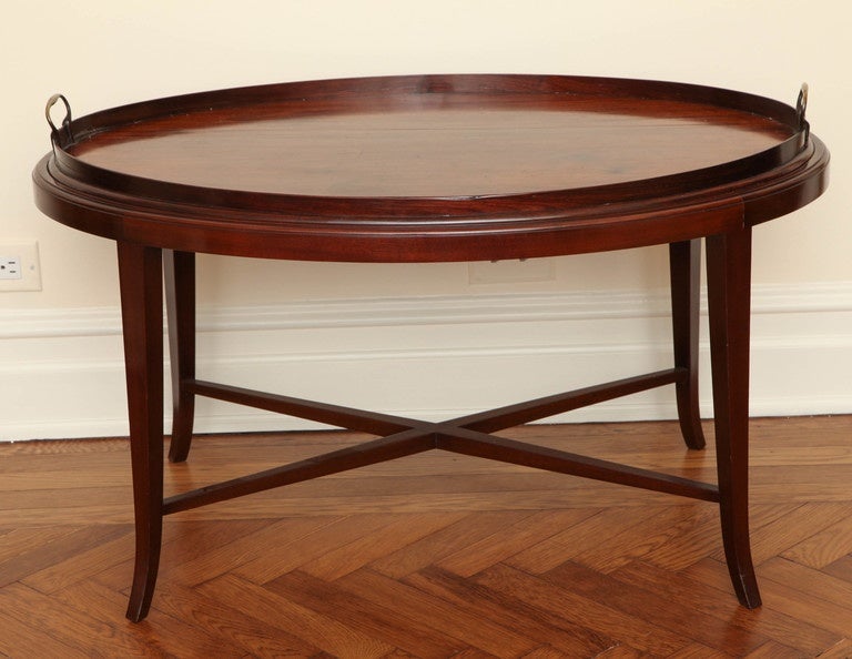 The oval mahogany tray mounted with brass carrying handles, on a conforming stand of a later date with felt-lined top on tapering legs joined by an X-form stretcher.