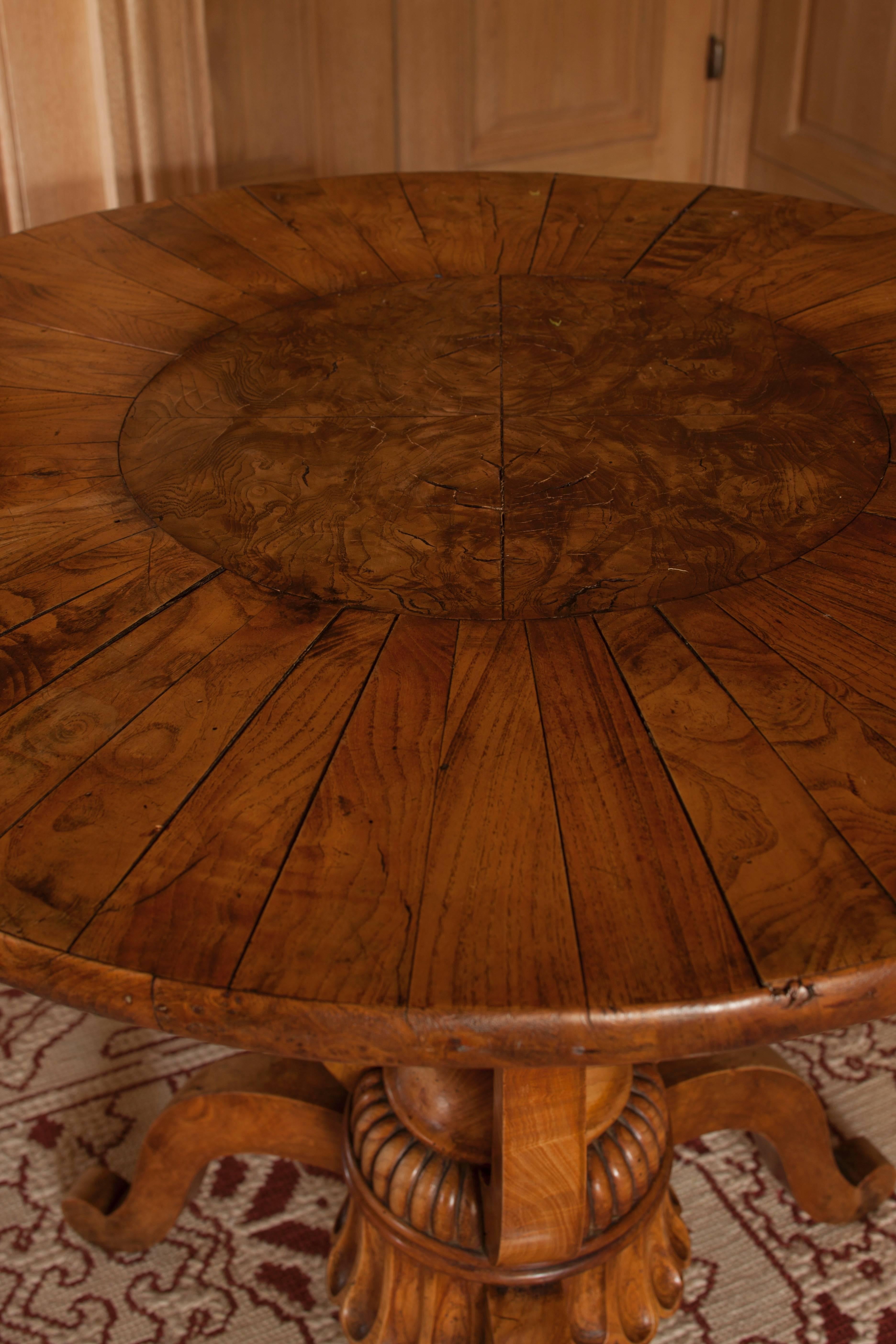 The round top centered by a burl walnut roundel set off by radiating veneers; raised on incurving supports joined by a reeded knob-form finial, issuing three downswept legs.