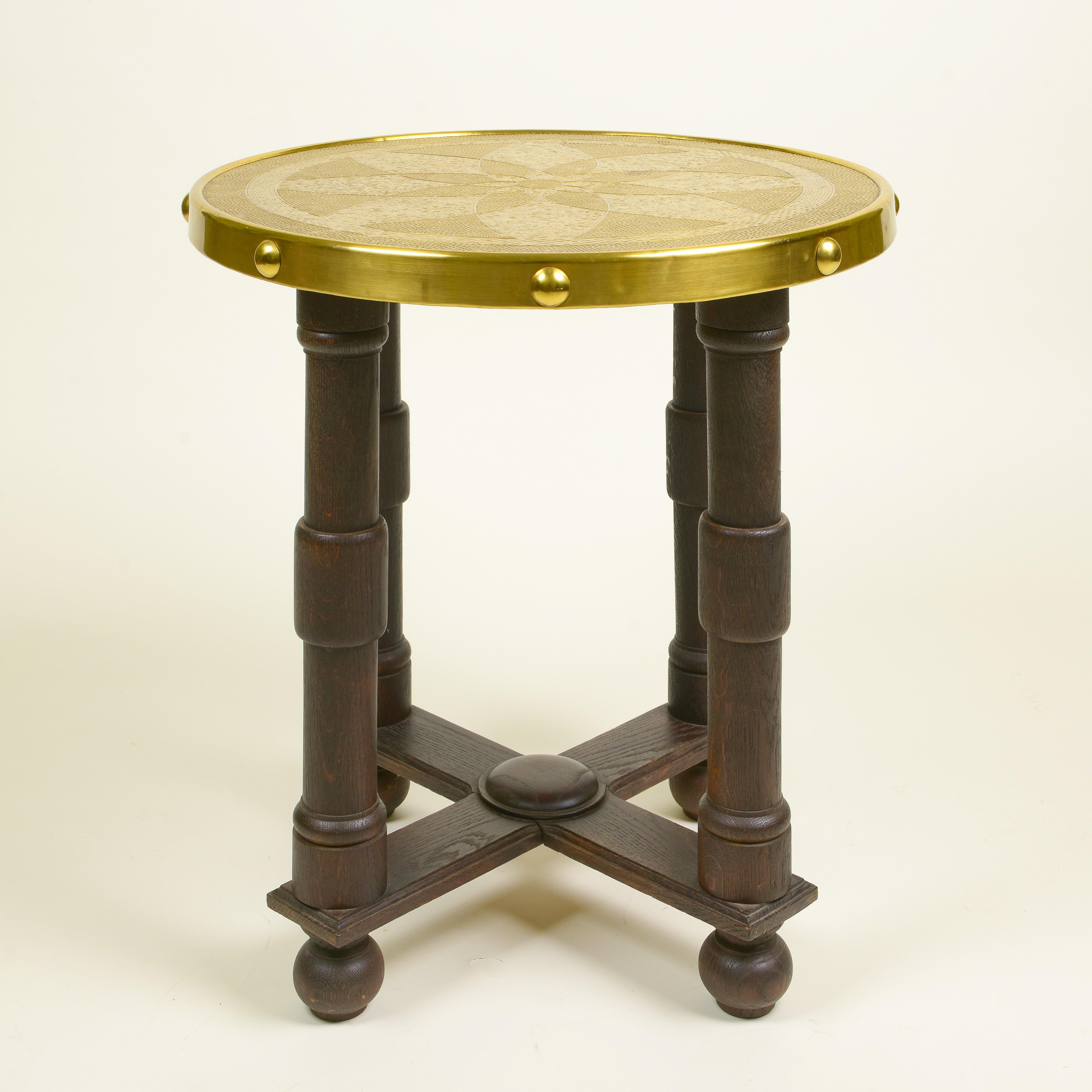 Unusual and handsome piece; the round dished brass top embossed and etched with a stylized flowerhead on a punched ground with stud-mounted edge; raised on four turned supports; on an X-form stretcher and turned bun feet.