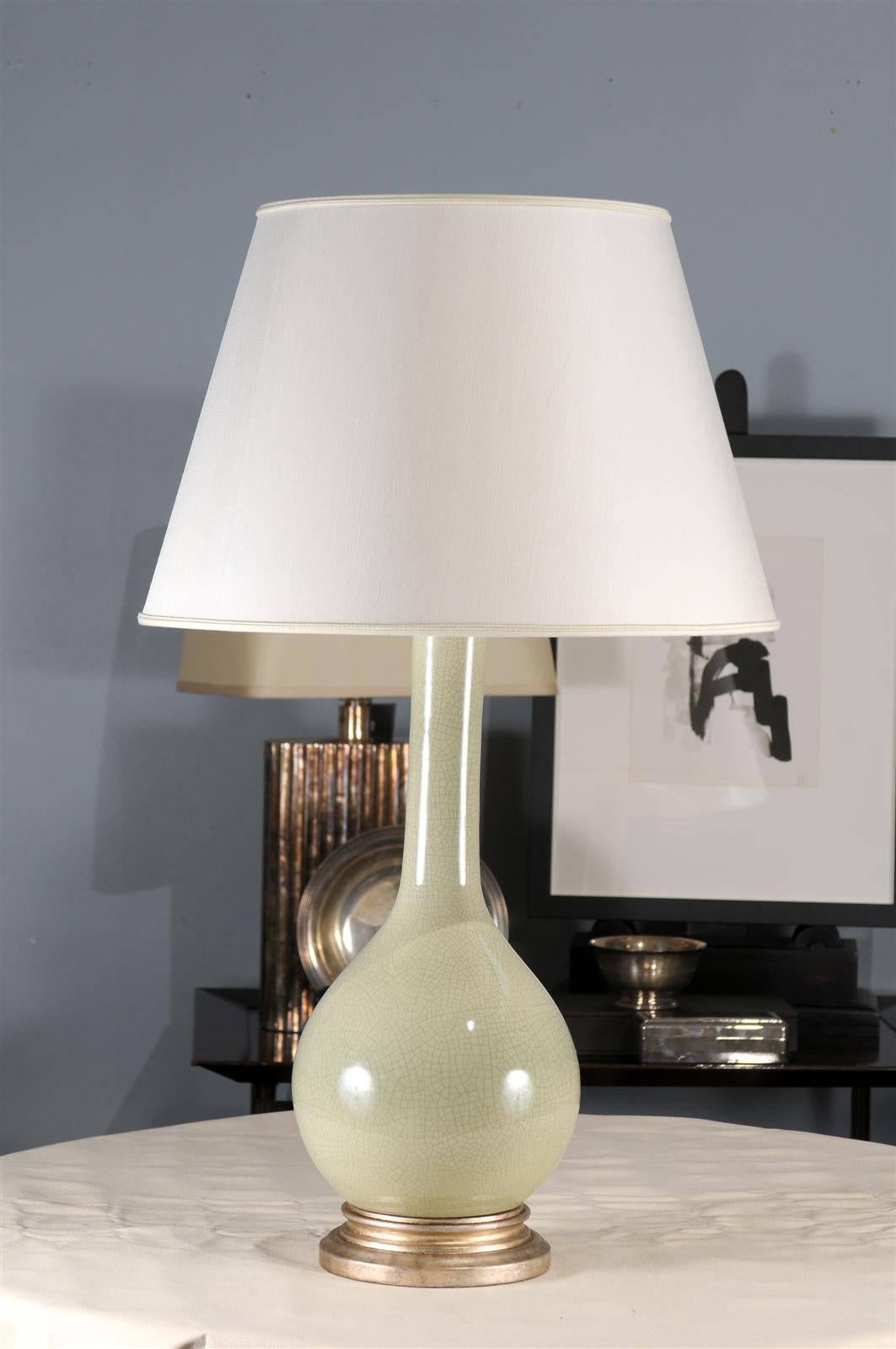 The Grande bottle lamp features a graceful swan neck that is suitable for any environment. The turned wood base is a silver/gold mottled finish. This lamp has an ivory chinette shade.