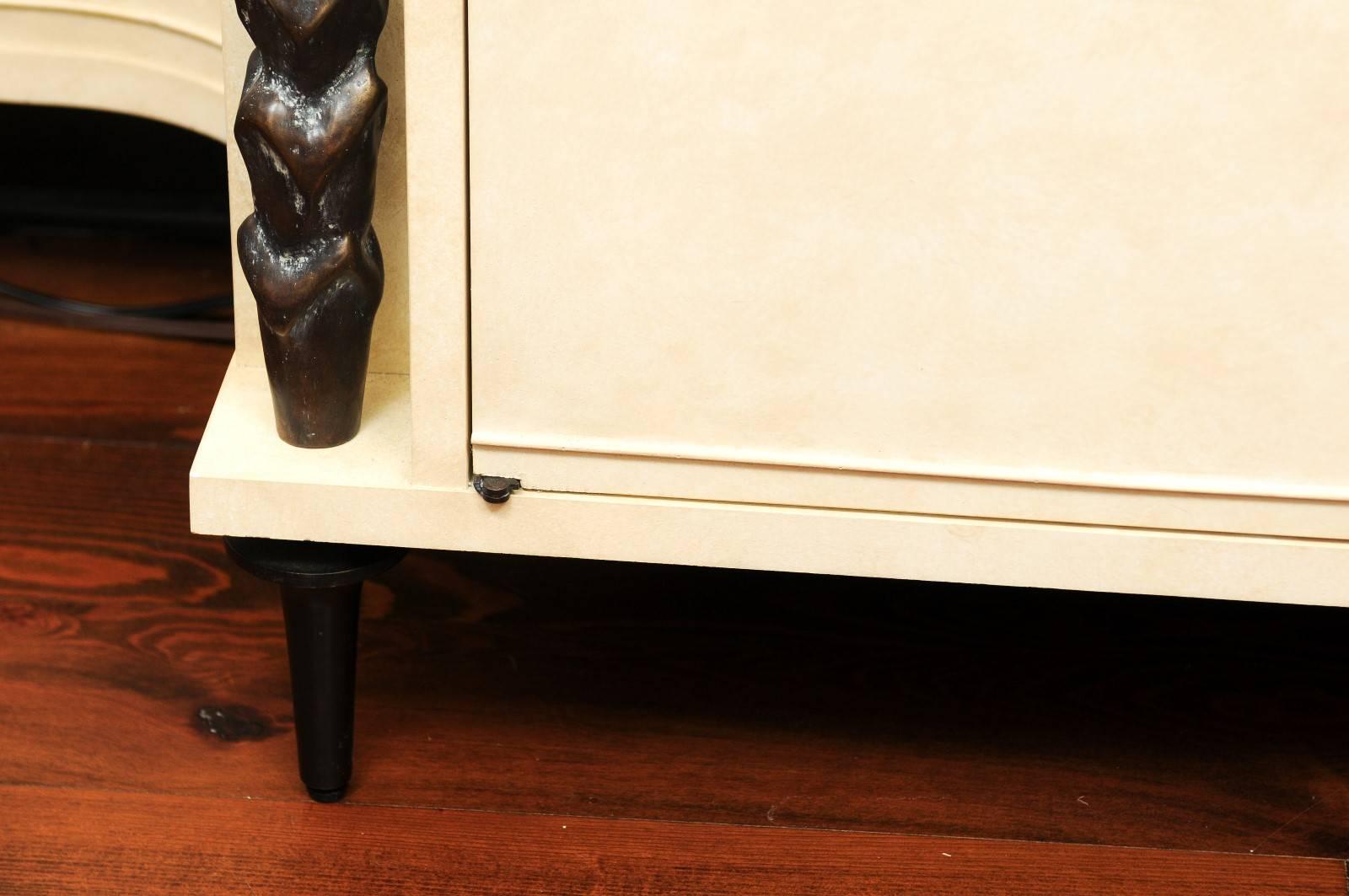 An Indochine buffet or cabinet designed by Andre Arbus and made by Baker. Parchment on hardwood with decorative bronze columns, feet and ornament. Two doors concealing shelved storage and a fitted flatware drawer.