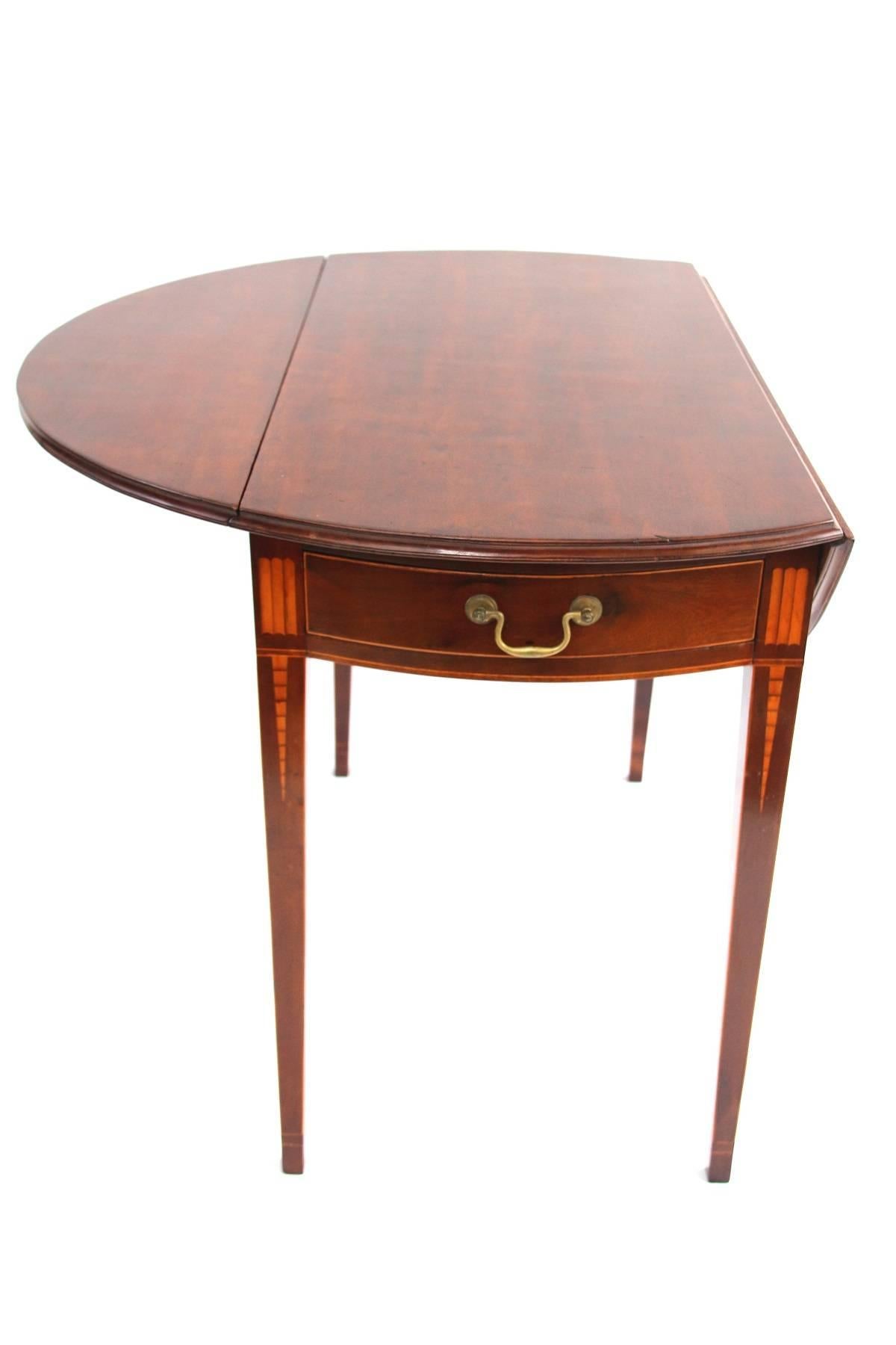 Mahogany and mahogany veneer inlaid pembroke table, the oval drop-leaf top above a bowed skirt with drawer flanked by book-end panels on the icicle-inlaid square tapering legs. 

Old brasses, refinished.

Connecticut, circa 1800.

Measures: