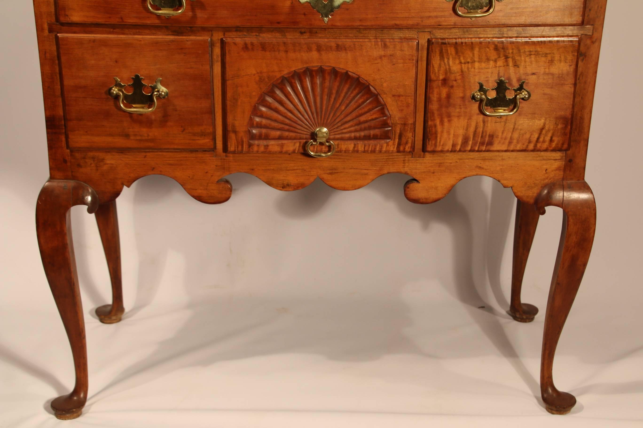 Queen Anne Tiger maple highboy. The upper dovetailed case with molded cornice over five long graduated drawers, fitted to the two waist-molded case of a long drawer over three aligned short drawers, the centermost fan-carved, above the scalloped