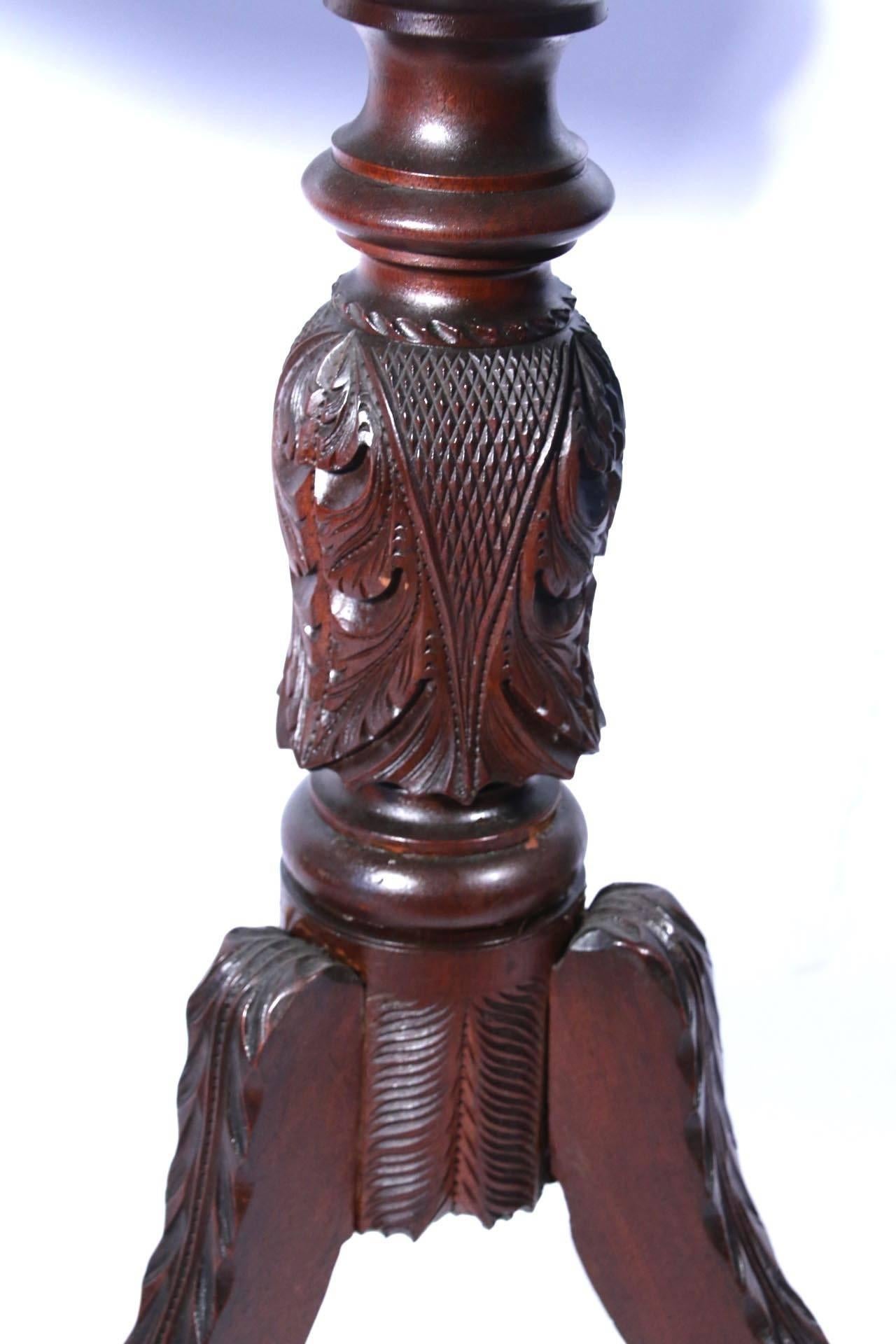 Classical carved mahogany tilt-top light stand, the shaped top on vase- and ring-turned support carved with acanthus leaves and sawtooth detail on a tripod base of waterleaf-carved scrolling legs. 

Probably New York, circa 1825.
