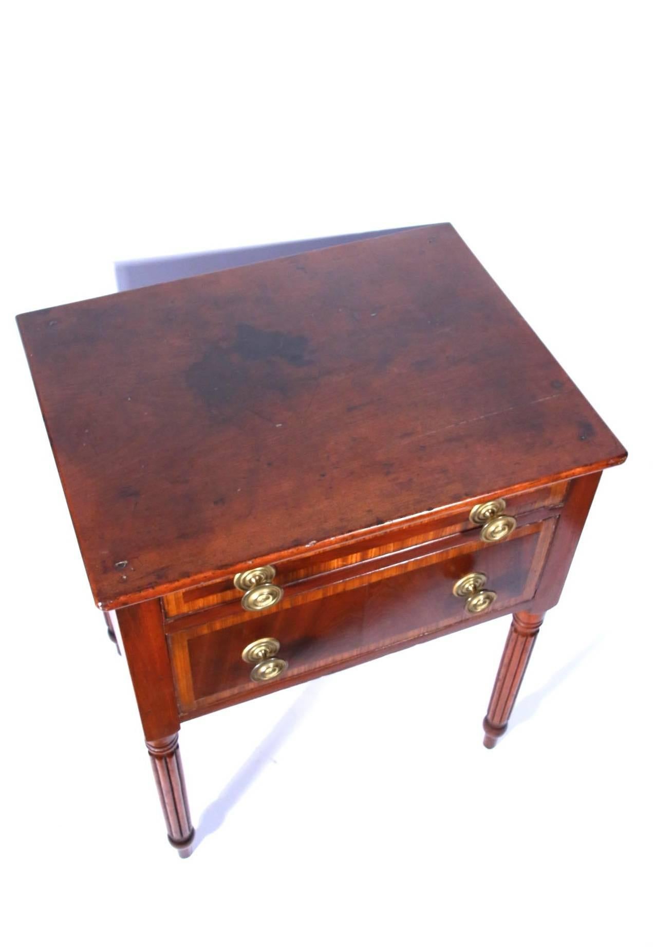 New England Sheraton mahogany and cherry two-drawer stand with rectangular top above the conforming case fitted with a bank of two drawers, each with inlay and mahogany veneer fronts, raised on tapered reeded legs terminating in bulbous
